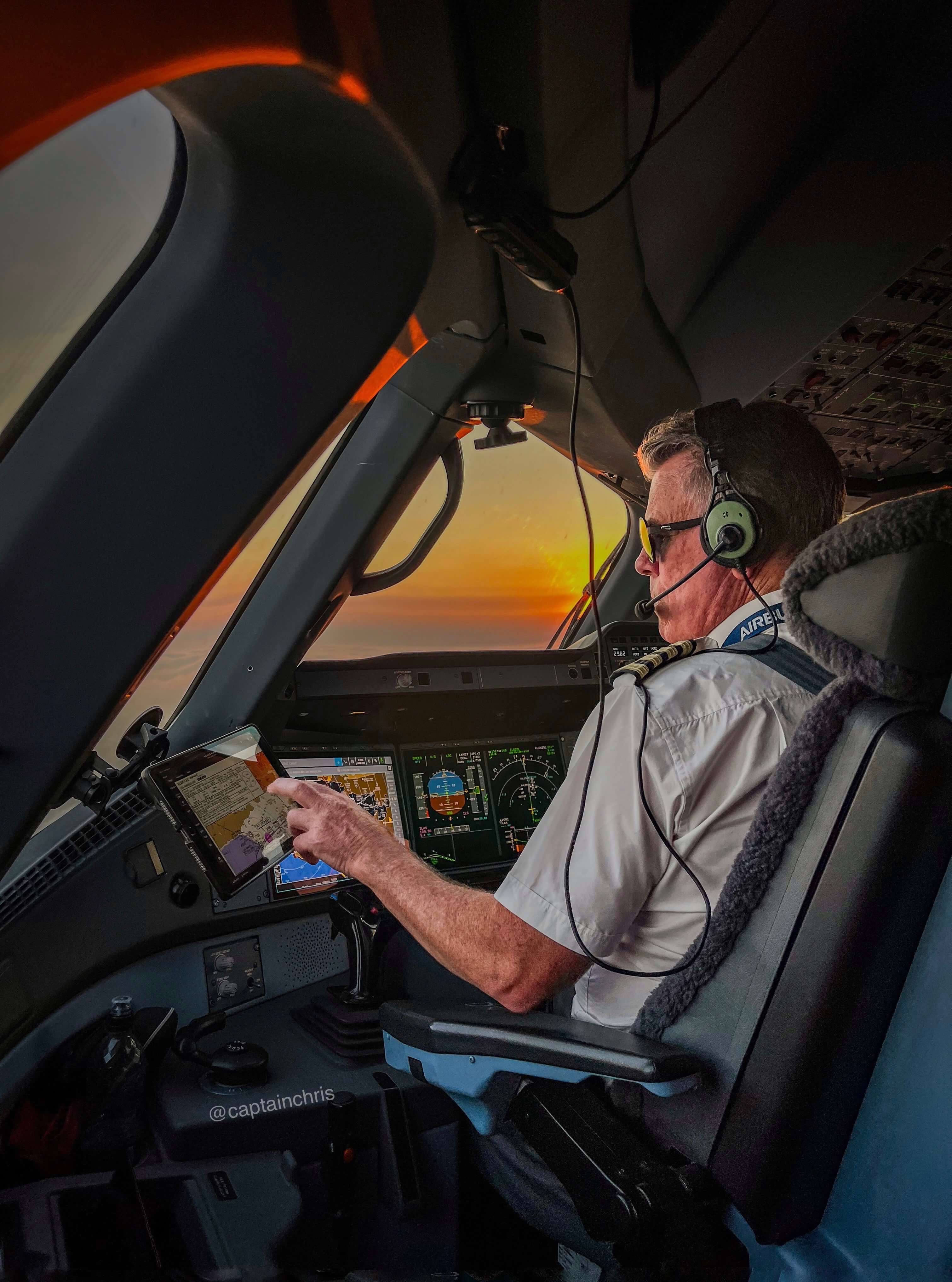 Captain Chris flying an aircraft at sunset inside the cockpit while monitoring navigation instruments.