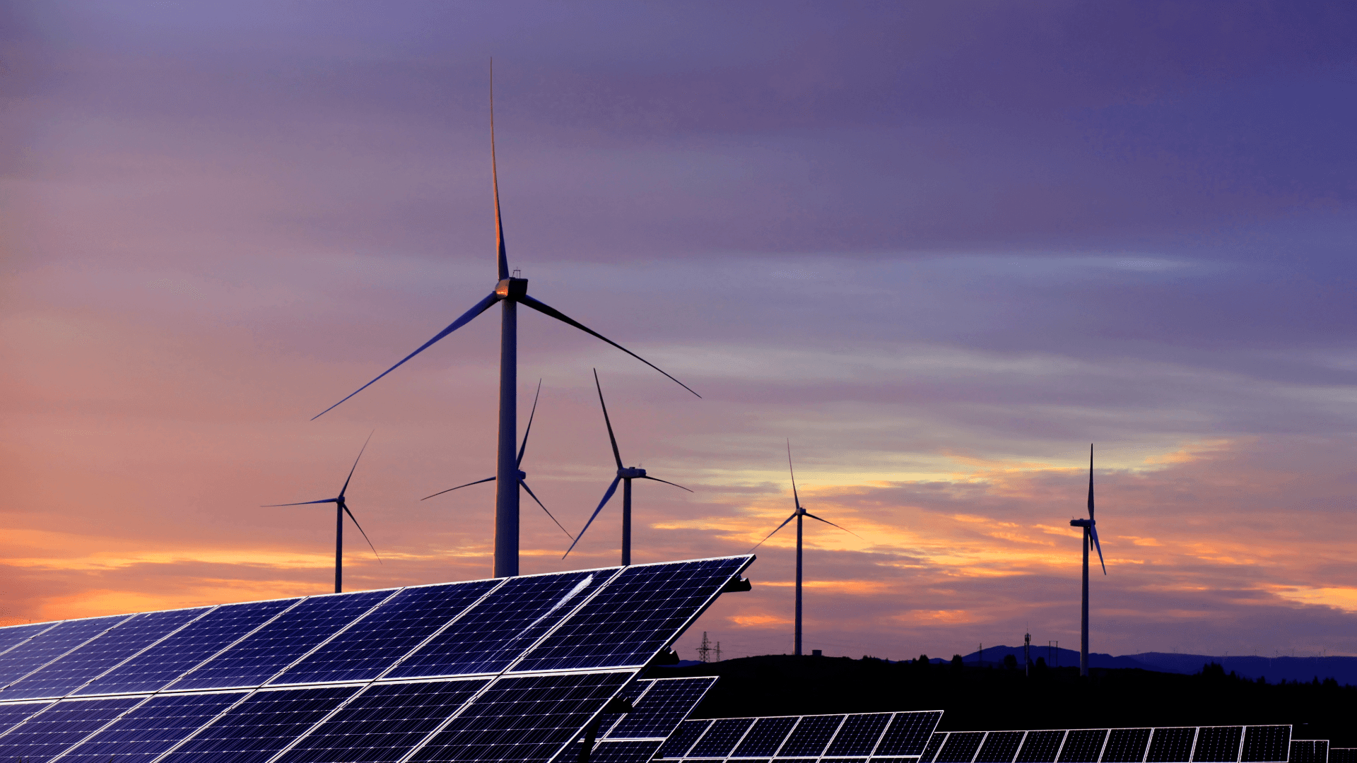 Solar panels and wind turbines generating renewable energy, representing net zero energy systems and sustainability skills required in UK facilities management.