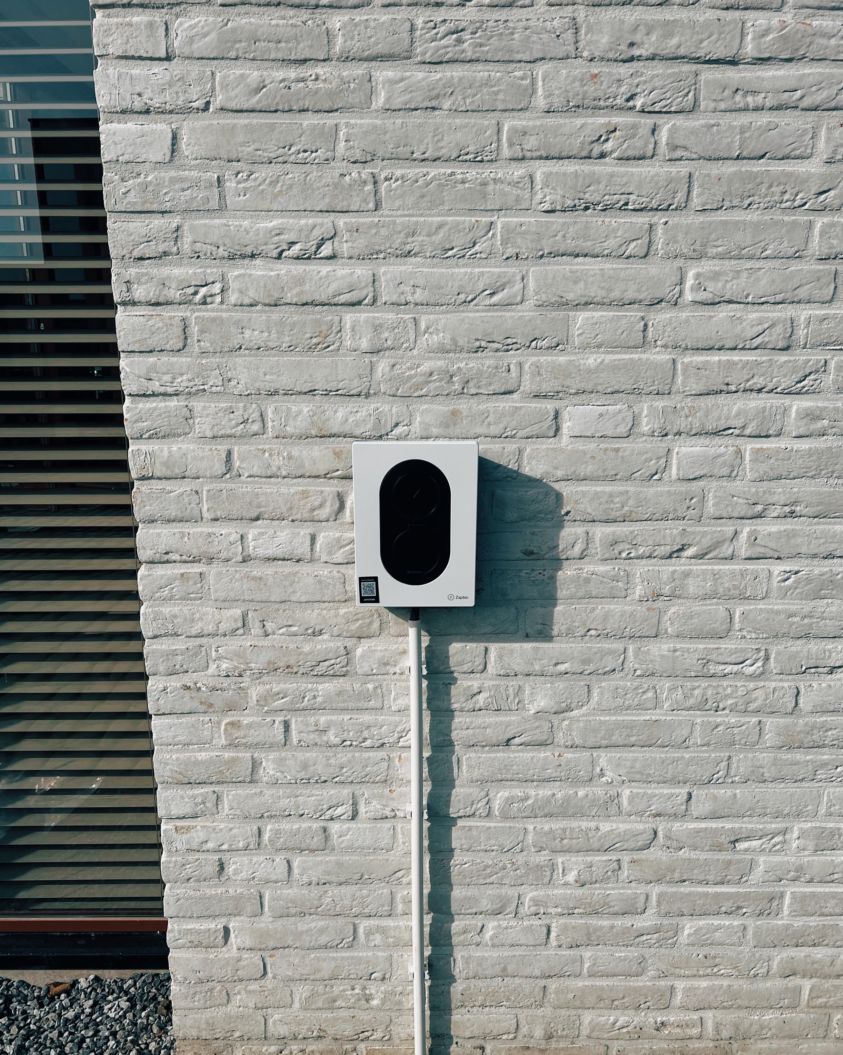 Modern building with glass walls, illuminated trees, and people overlooking a cityscape at sunset