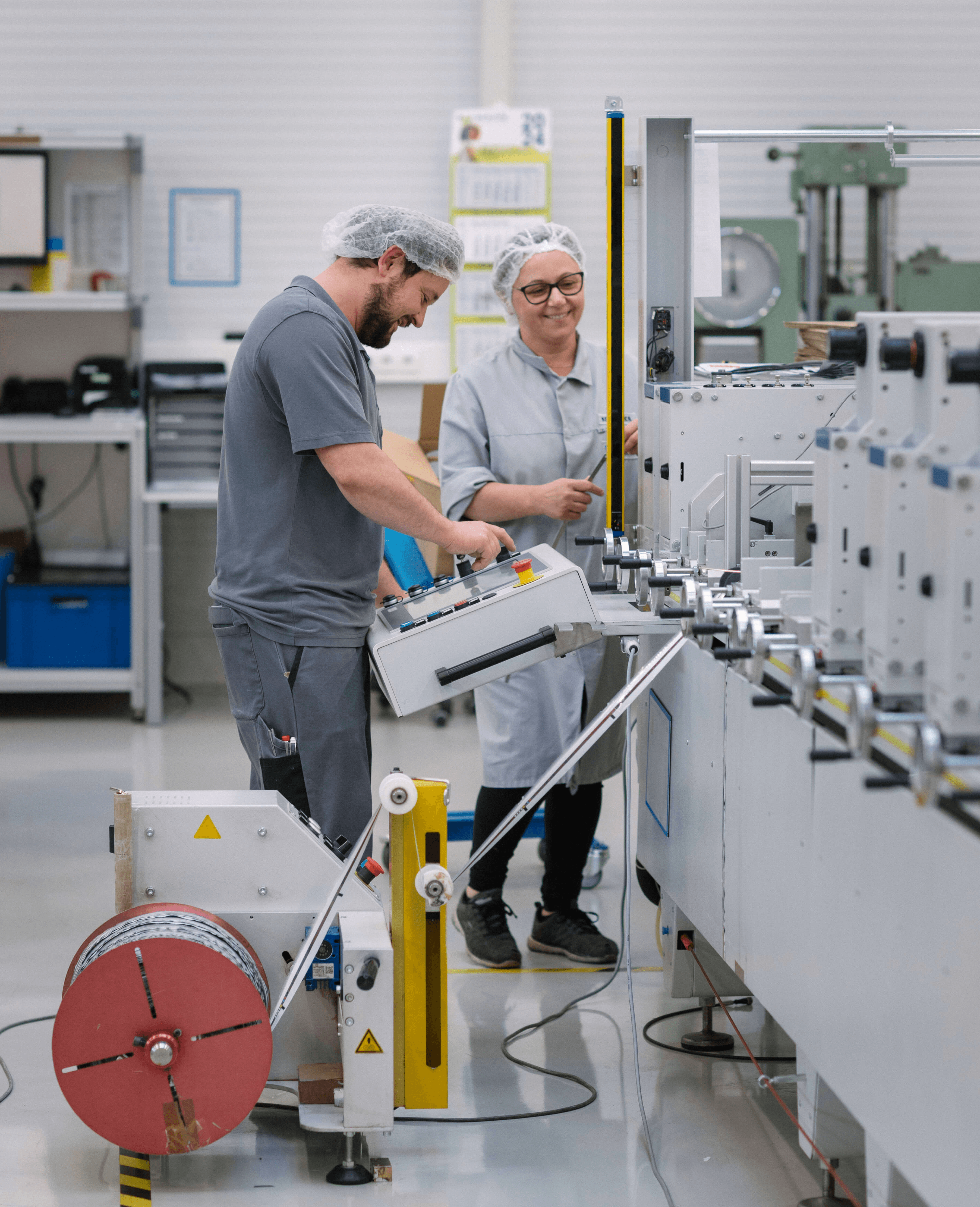 Two happy Scheyer employees working collaboratively on machinery in the production area.