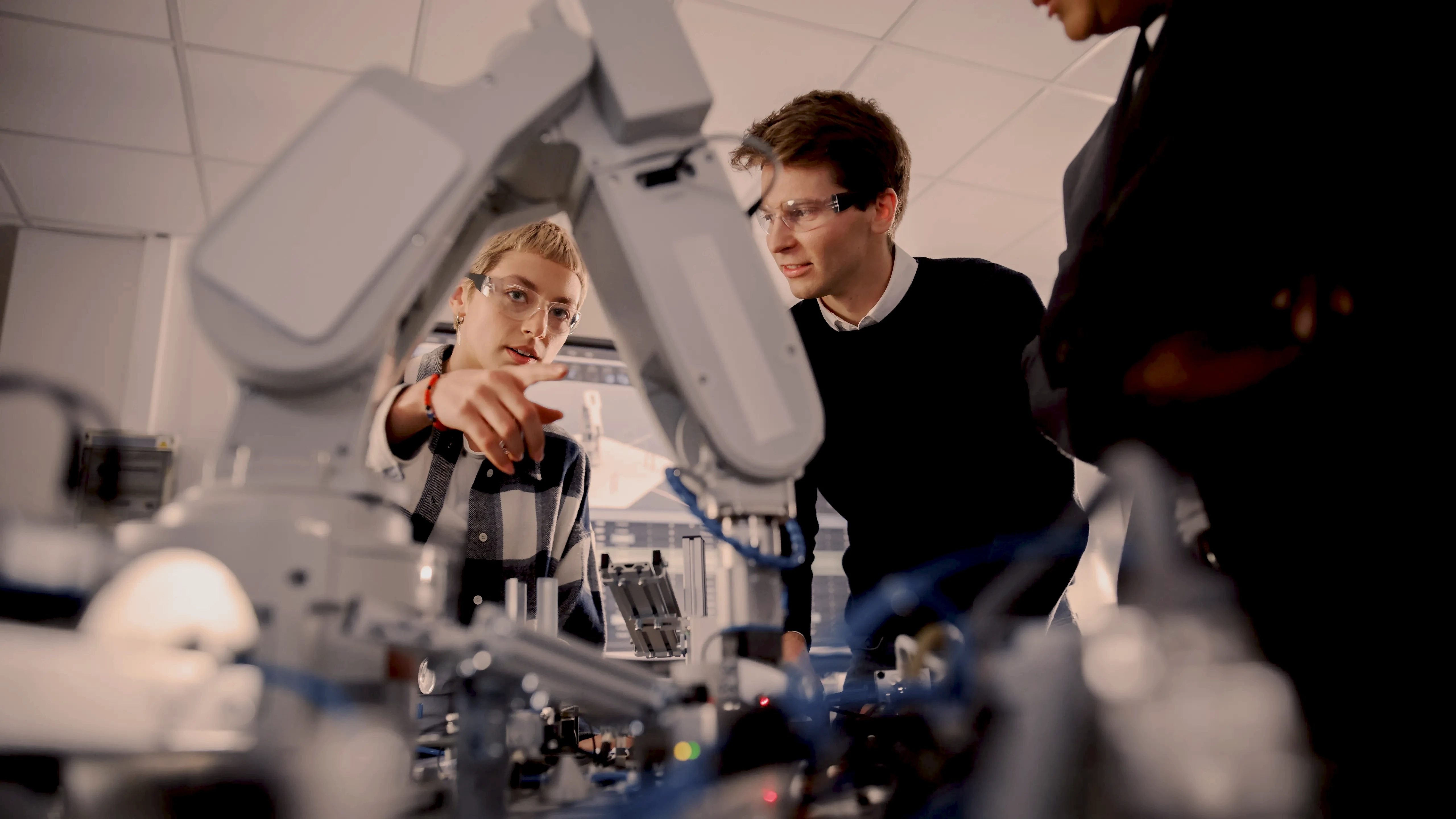 Two engineers examining a robot arm in a lab