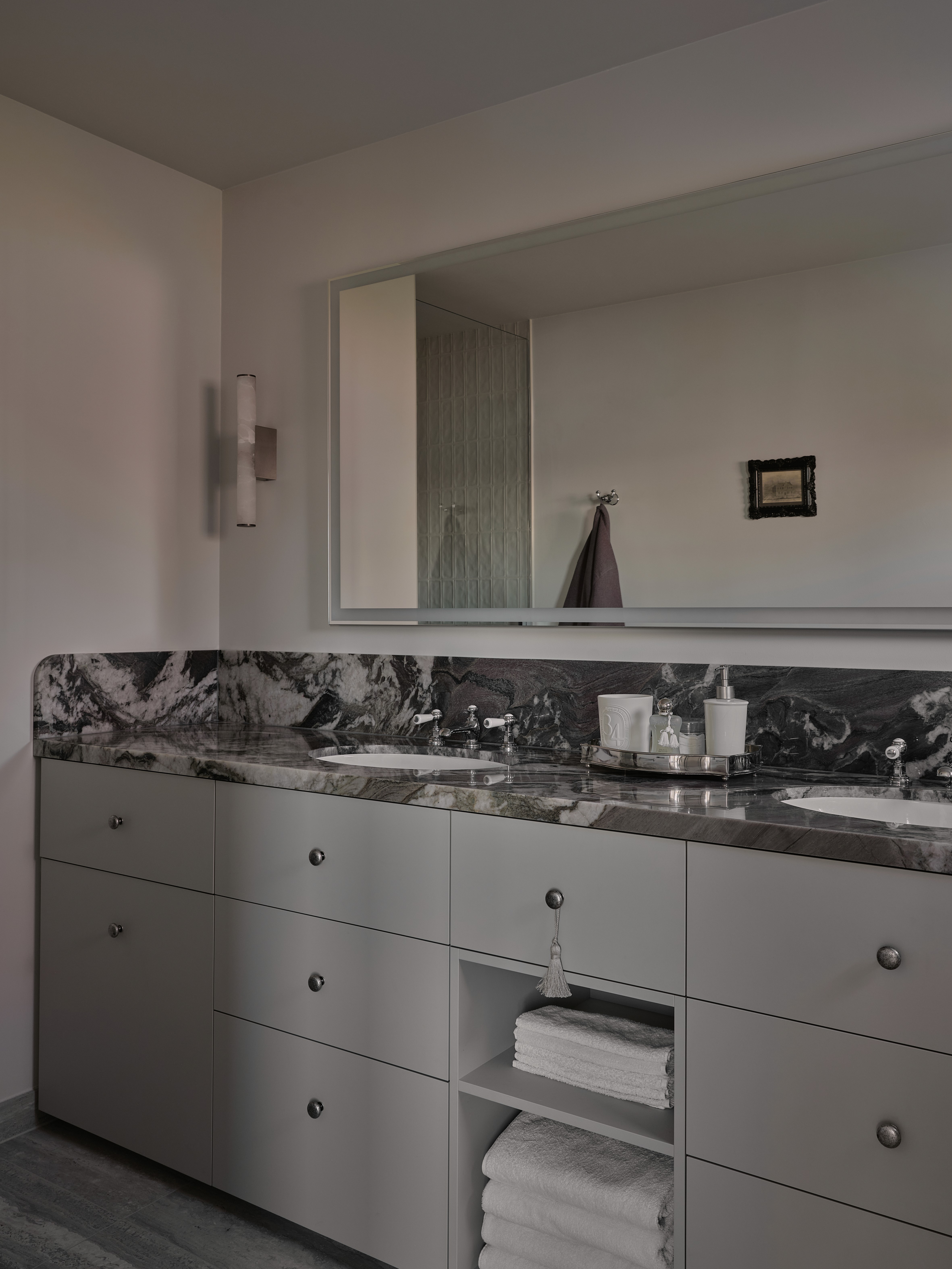 Primary bathroom vanity with grey marble countertop, undermount sinks, and brass hardware