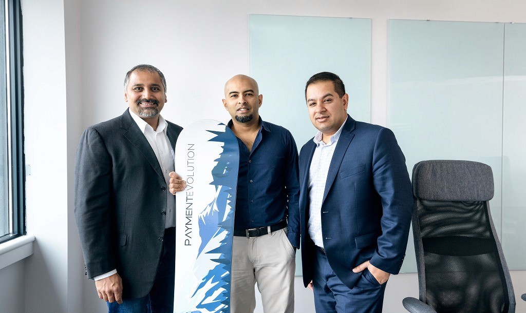 PaymentEvolution leadership team of three business executives with company-branded snowboard in modern office