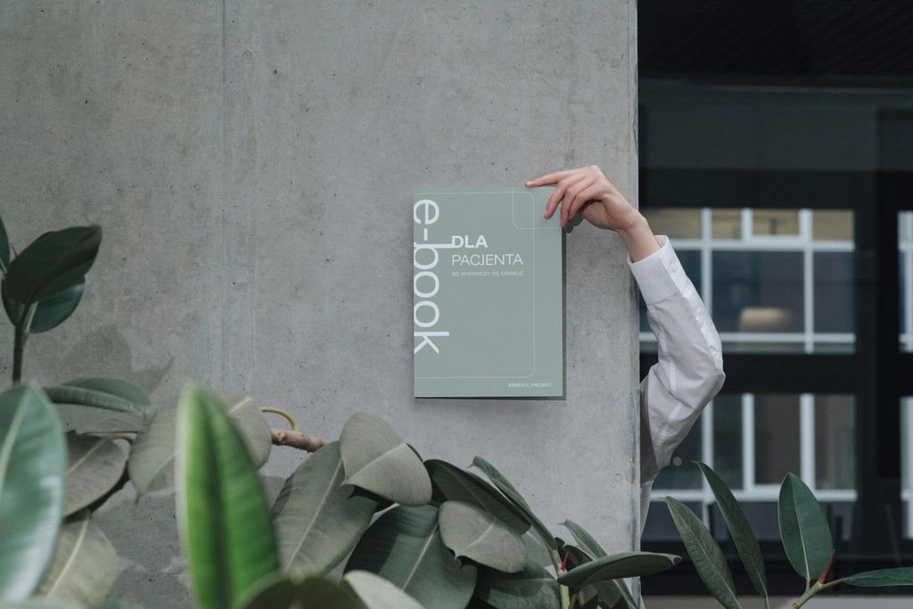broszura trzymana na tle ściany
