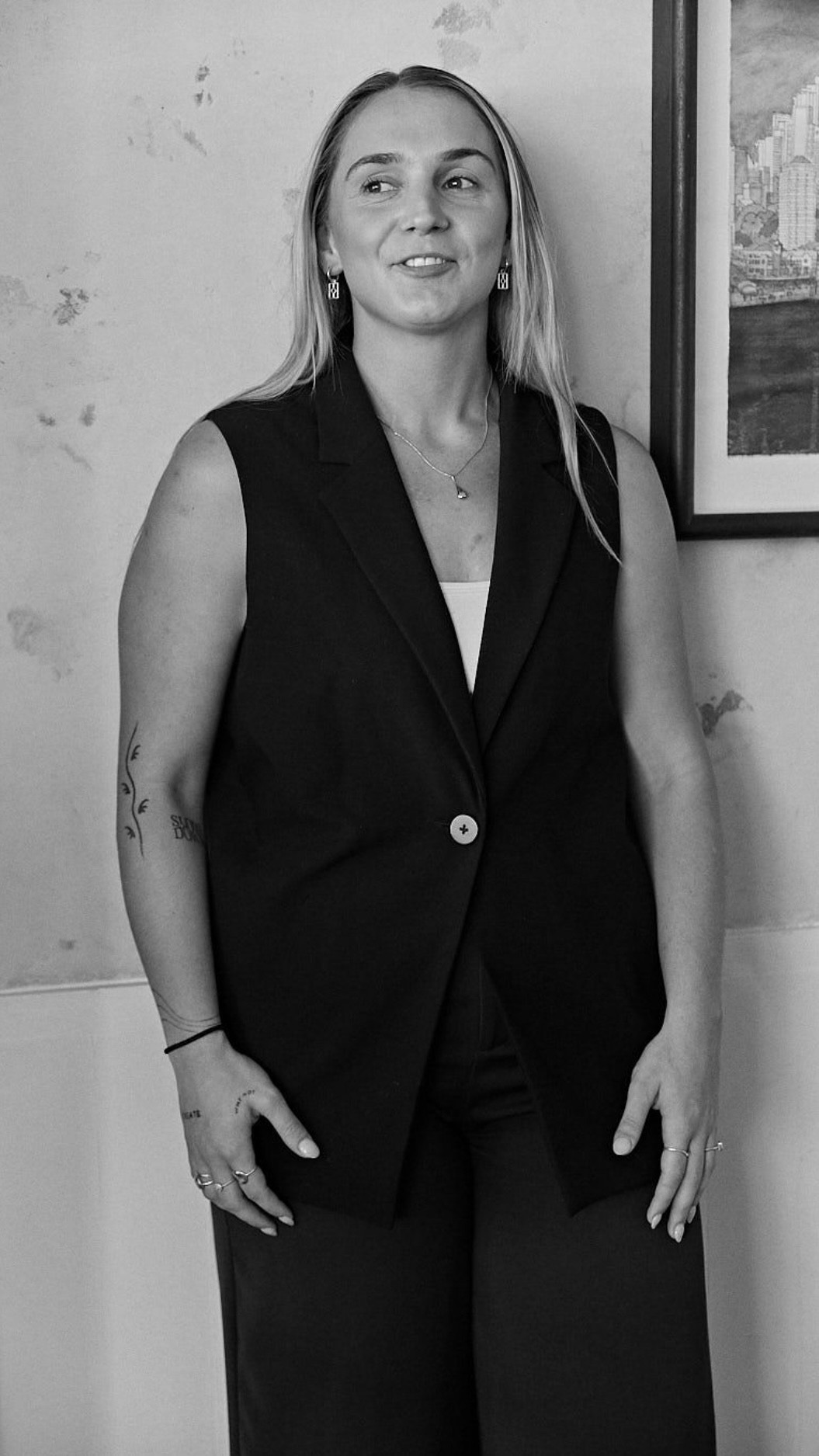 Person wearing a blue puffer jacket and red backpack standing in front of a light blue building on a city street.