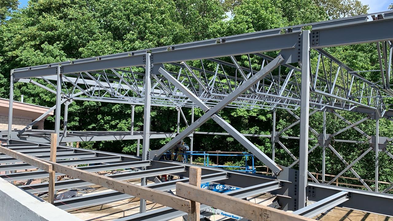 Steel beams, columns and diagonal bracing at a wooded construction site
