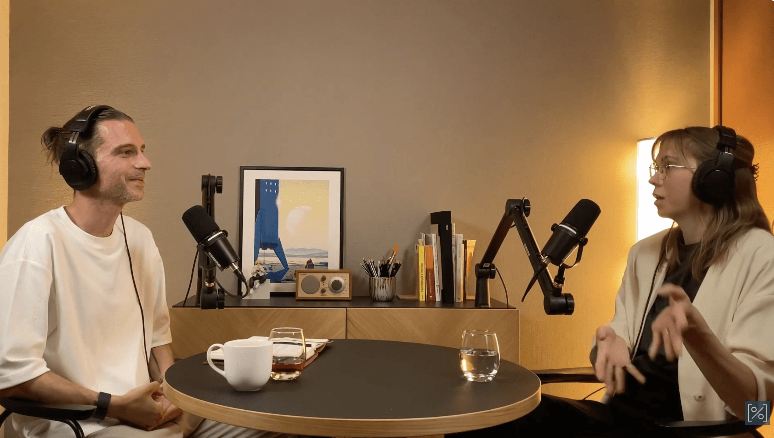 Podcast recording scene with two people seated at a table discussing design and life in Japan.