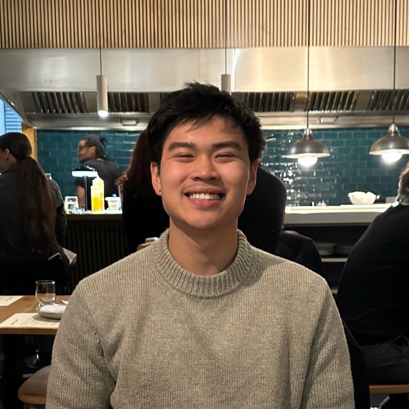 Man with short dark hair wearing a light green shirt, sitting near a window in soft light