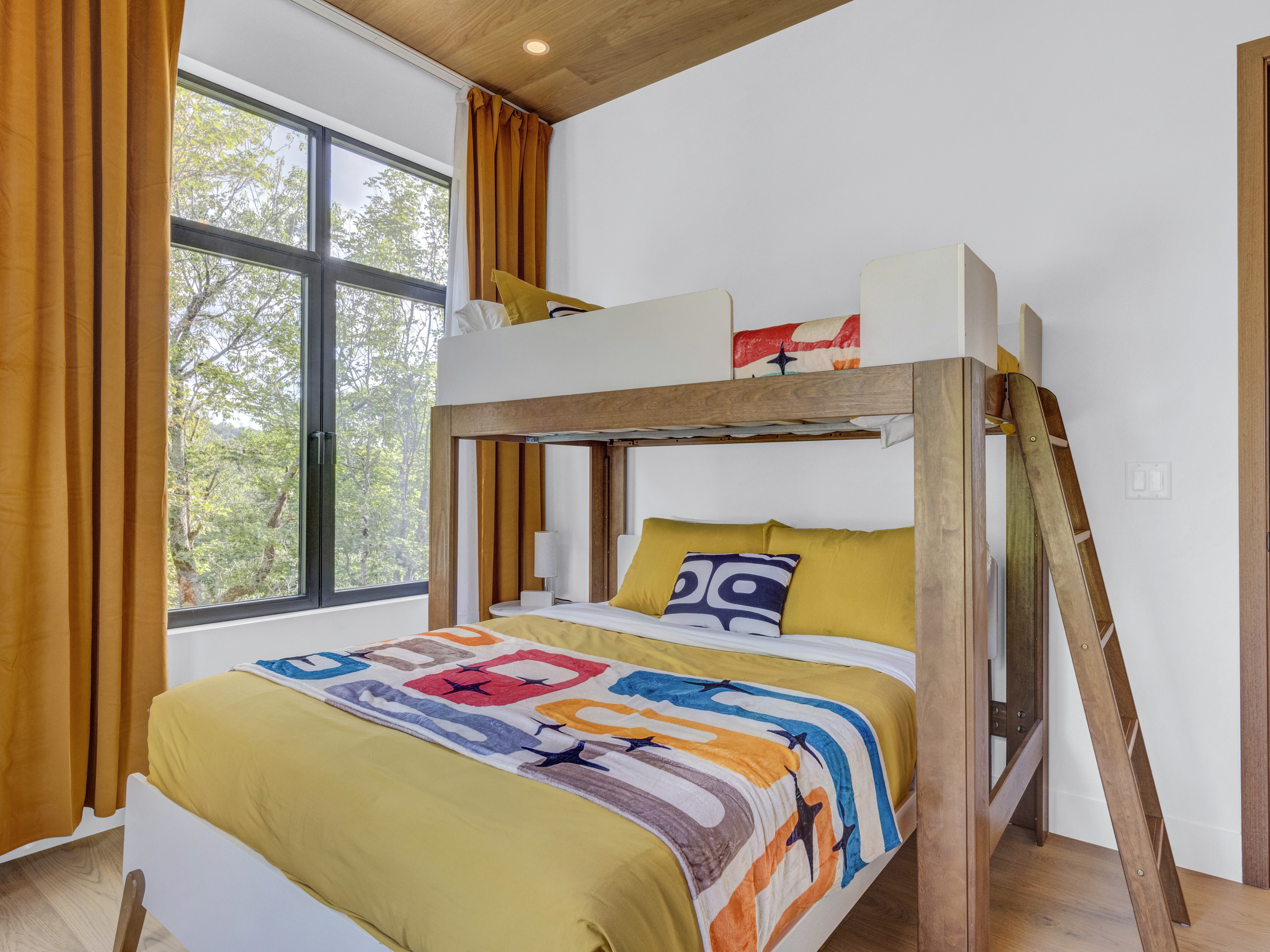 Interior shot of the bunk room showing the sturdy wood frame of the beds and the warm mustard-yellow accents
