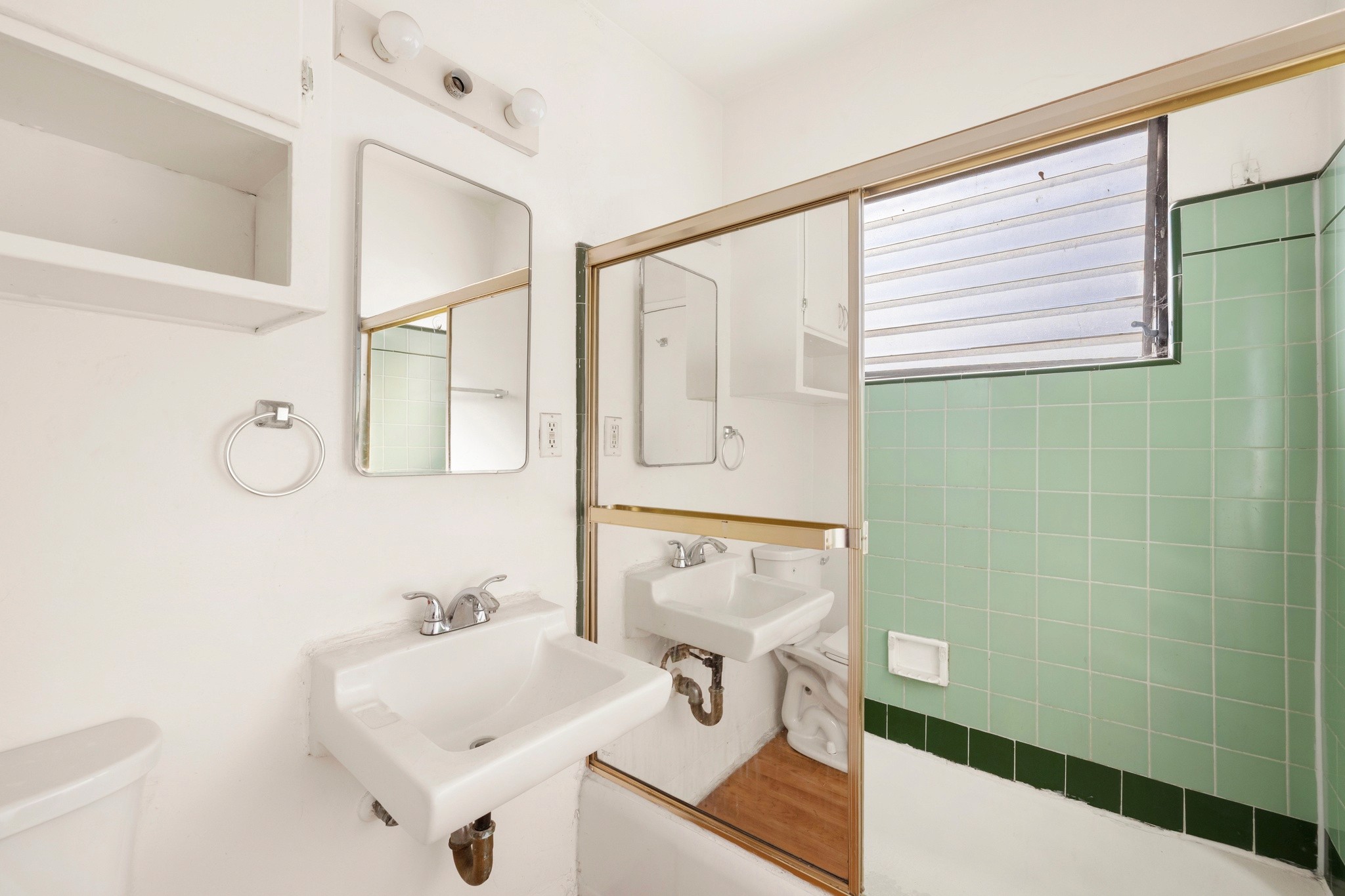 Bathroom with tiled shower, vanity, and mirrored closet doors at 436 Normandie Pl.