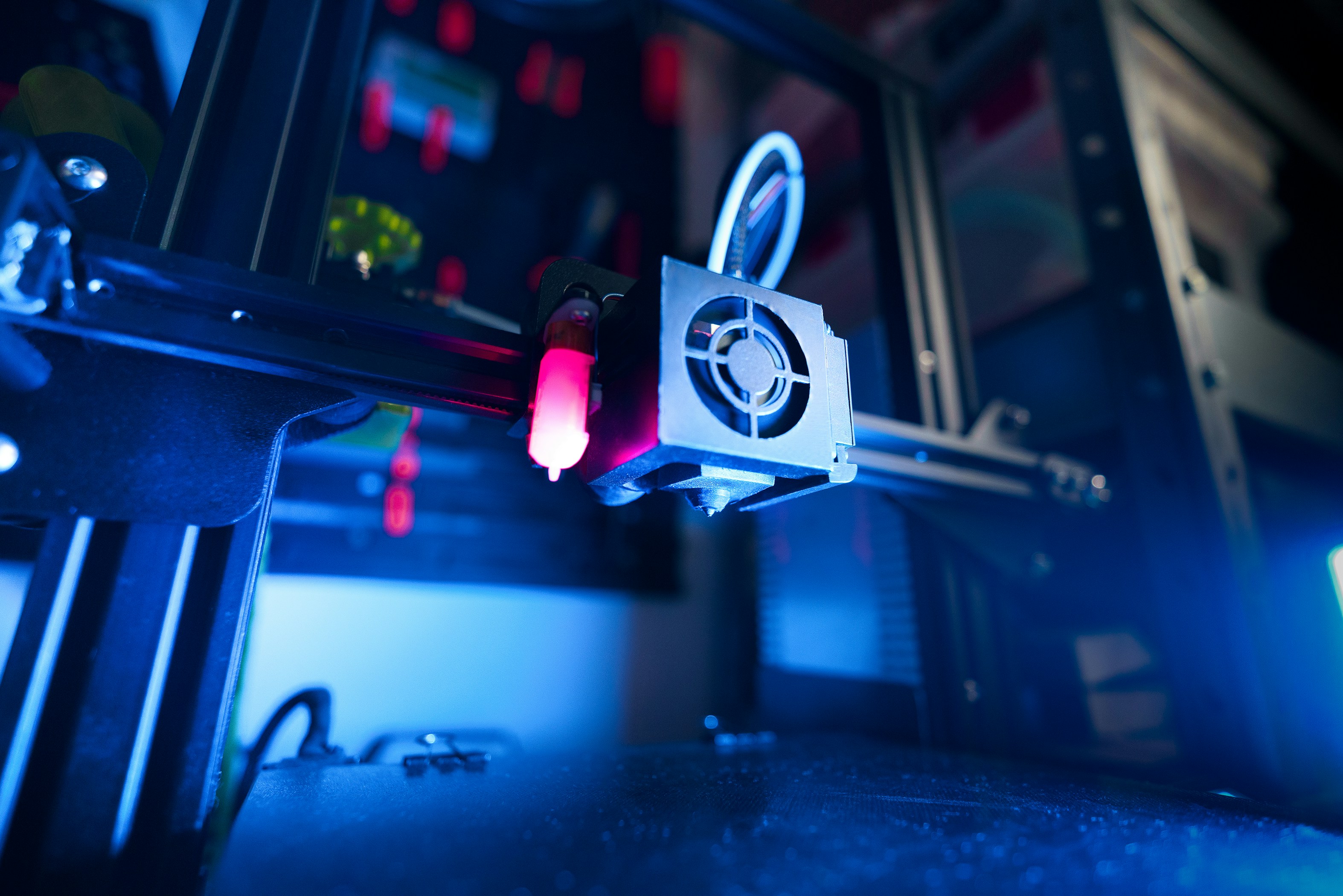Close-up of 3D printer extruder in a dimly lit setup with neon lighting effects