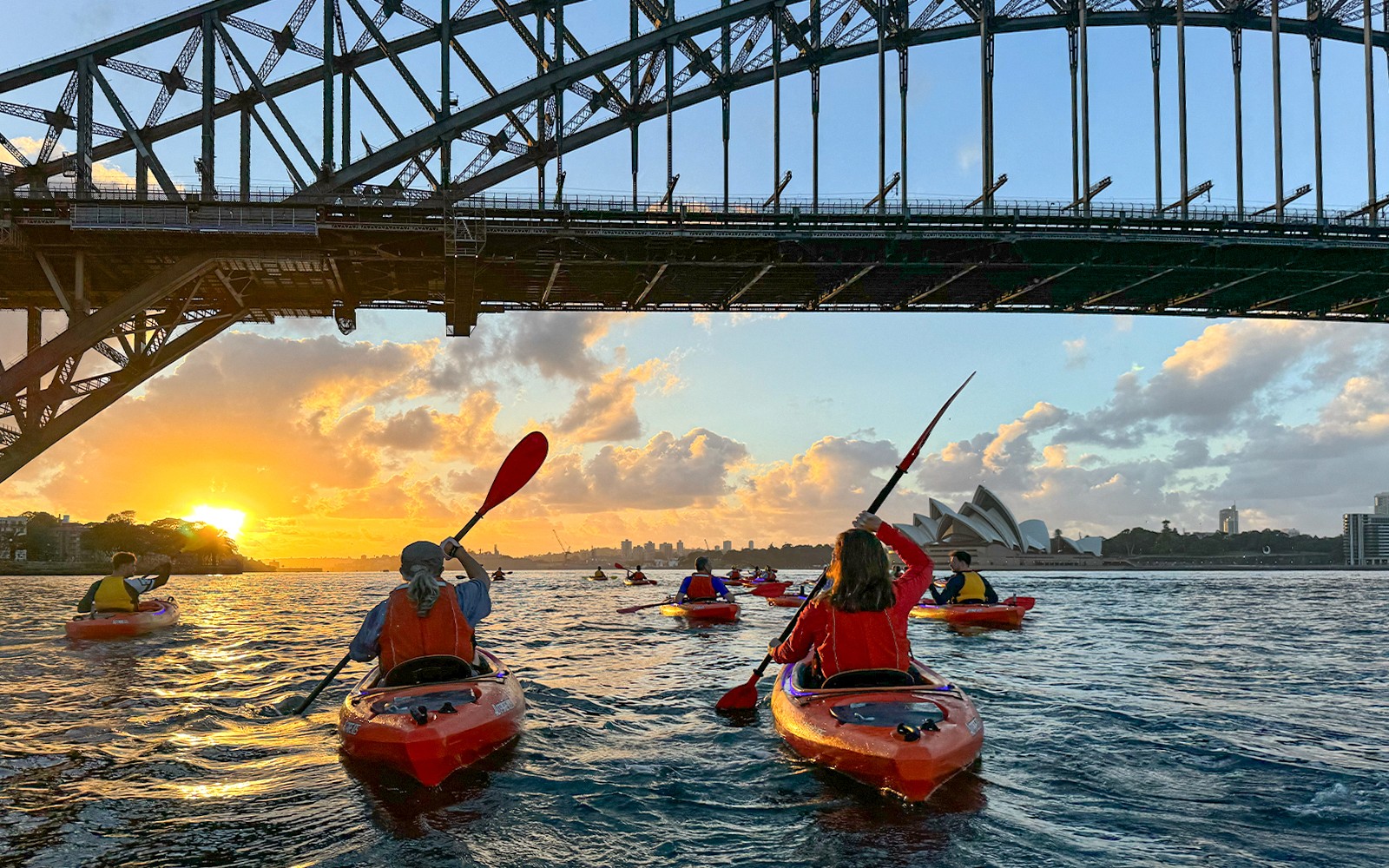 Group of people enjoying a sunrise paddle on Sydney Harbour with a breakfast picnic, with the iconic Sydney Opera House in the background