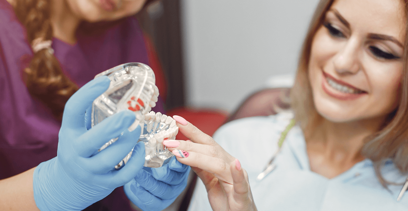 A dentist showing a patient a model of teeth with braces during a consultation about teeth alignment options