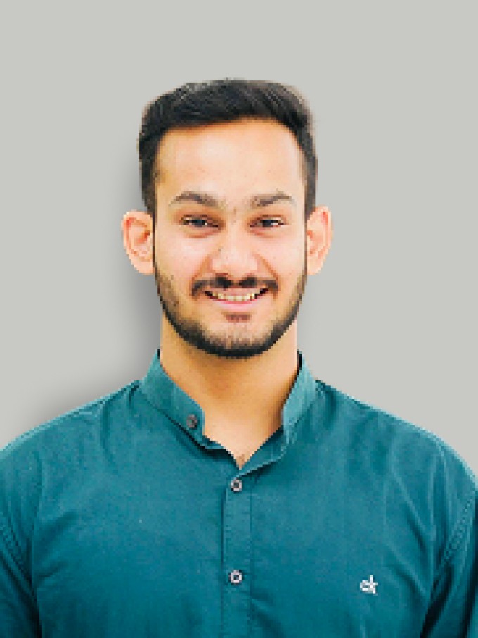 A woman with short curly hair wearing a black t-shirt looks into the camera.