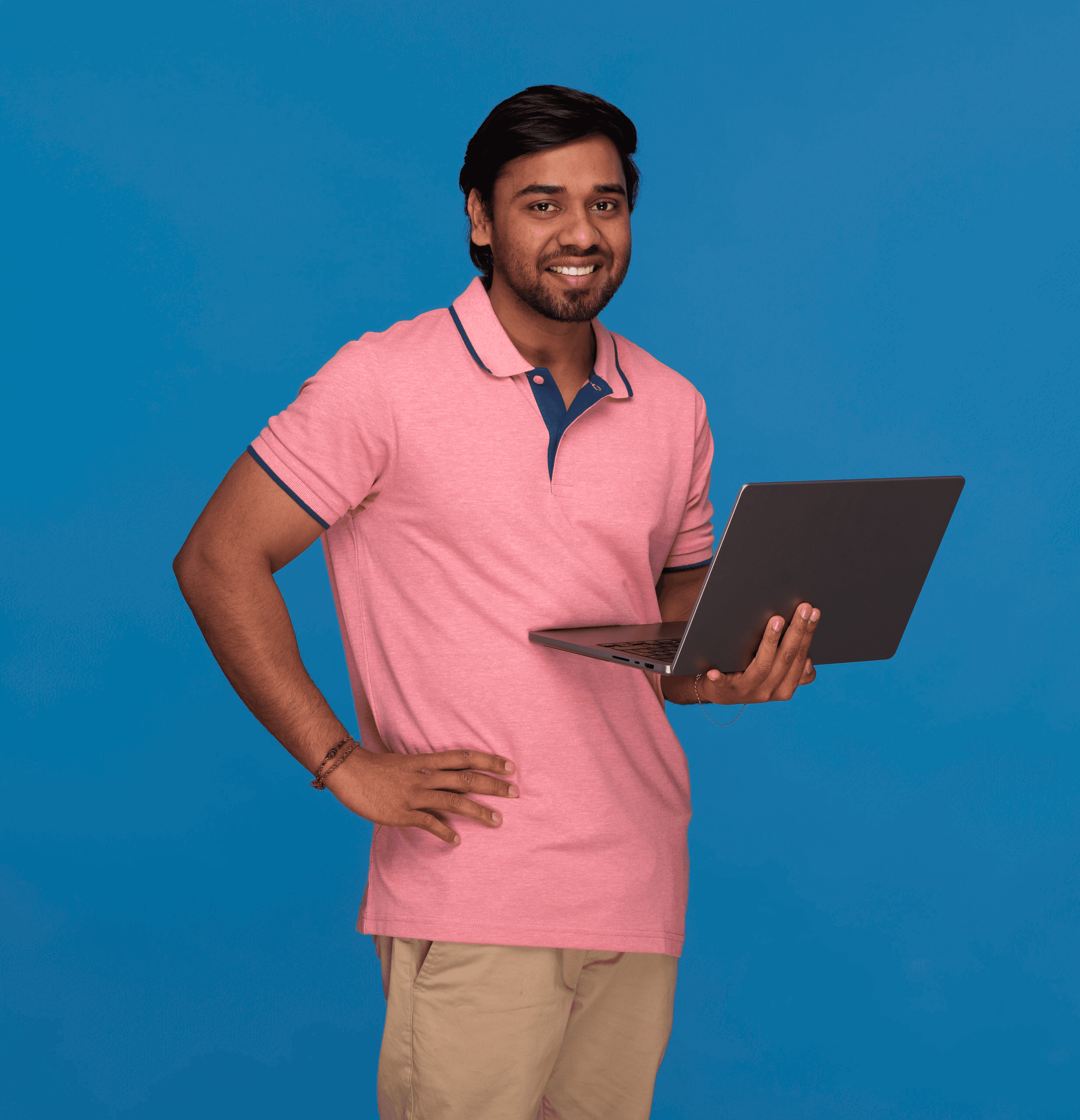 A smiling woman with her arms crossed, standing against a dark green background. She has long, dark hair.