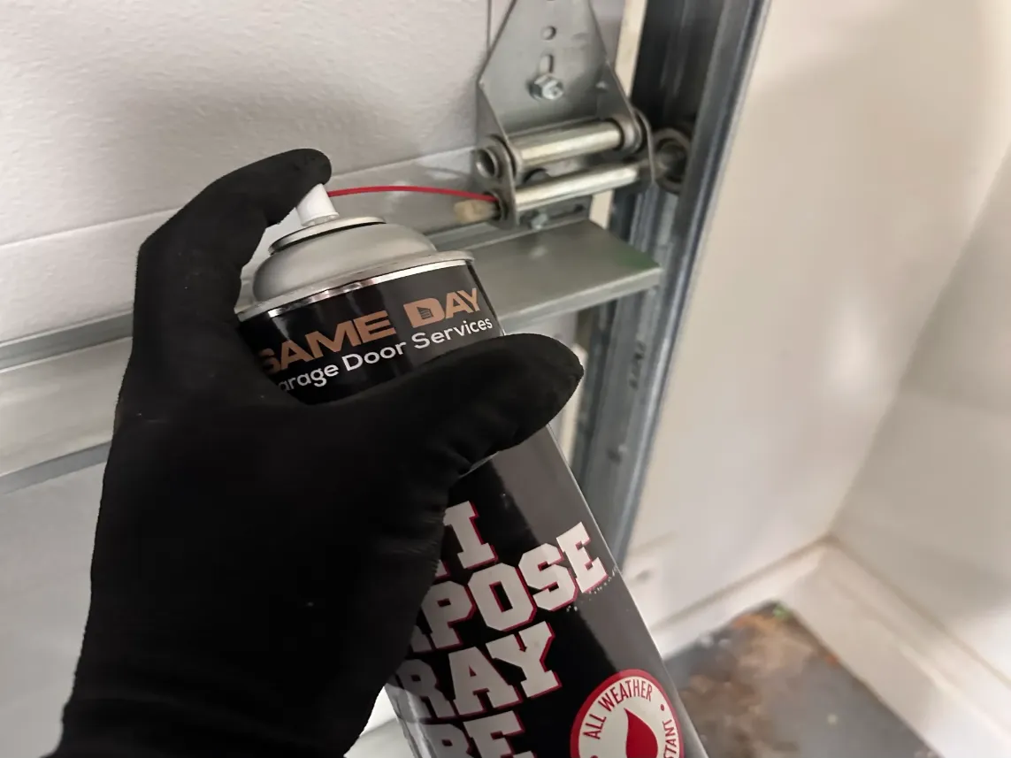 close up photo of a same day garage door services technician's hand hold a lubricating spray