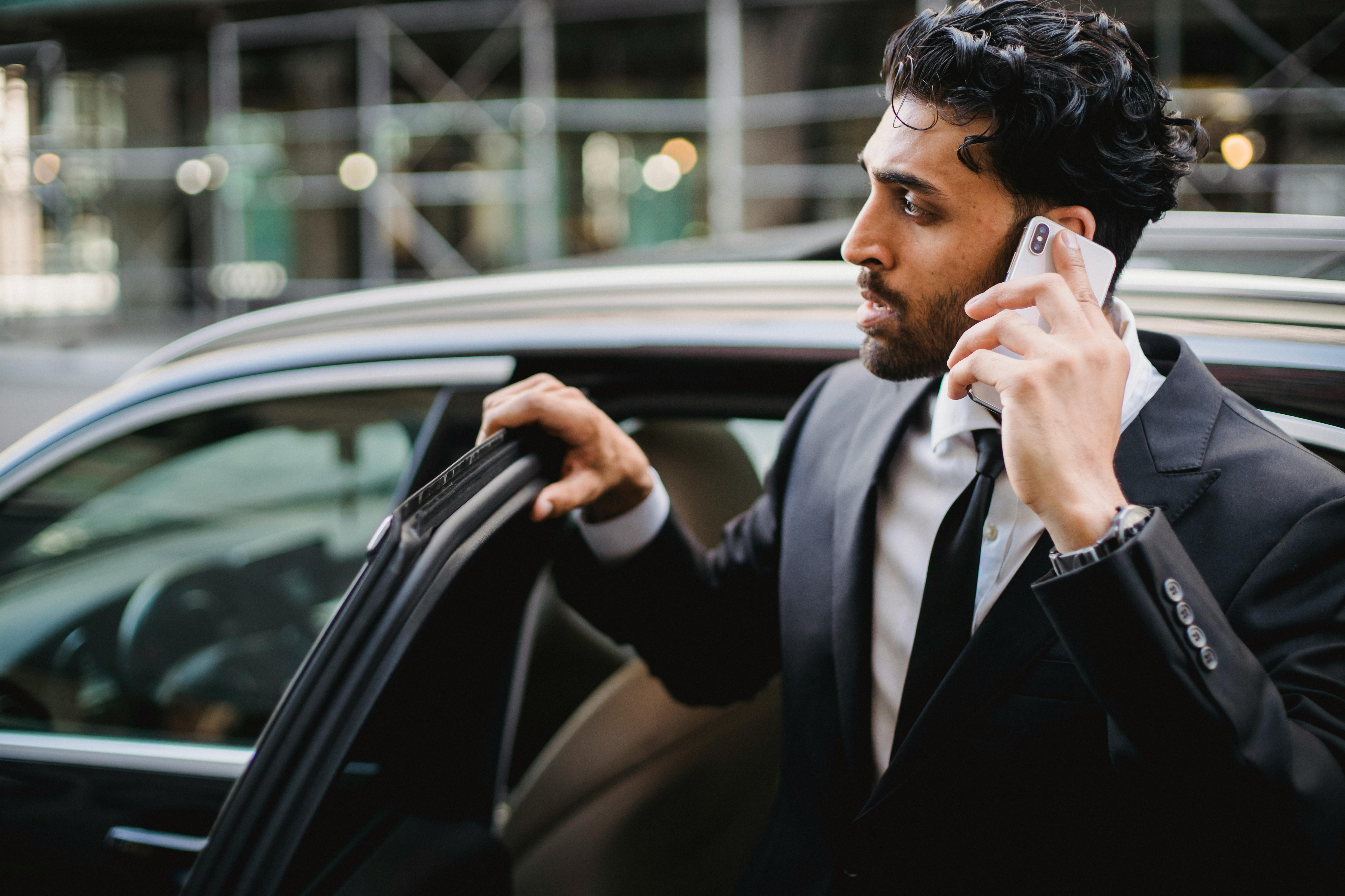 a-businessman-in-a-suit-talking-on-his-smartphone-while-exiting-a-vehicle. - ketut-subiyanto (pexels)