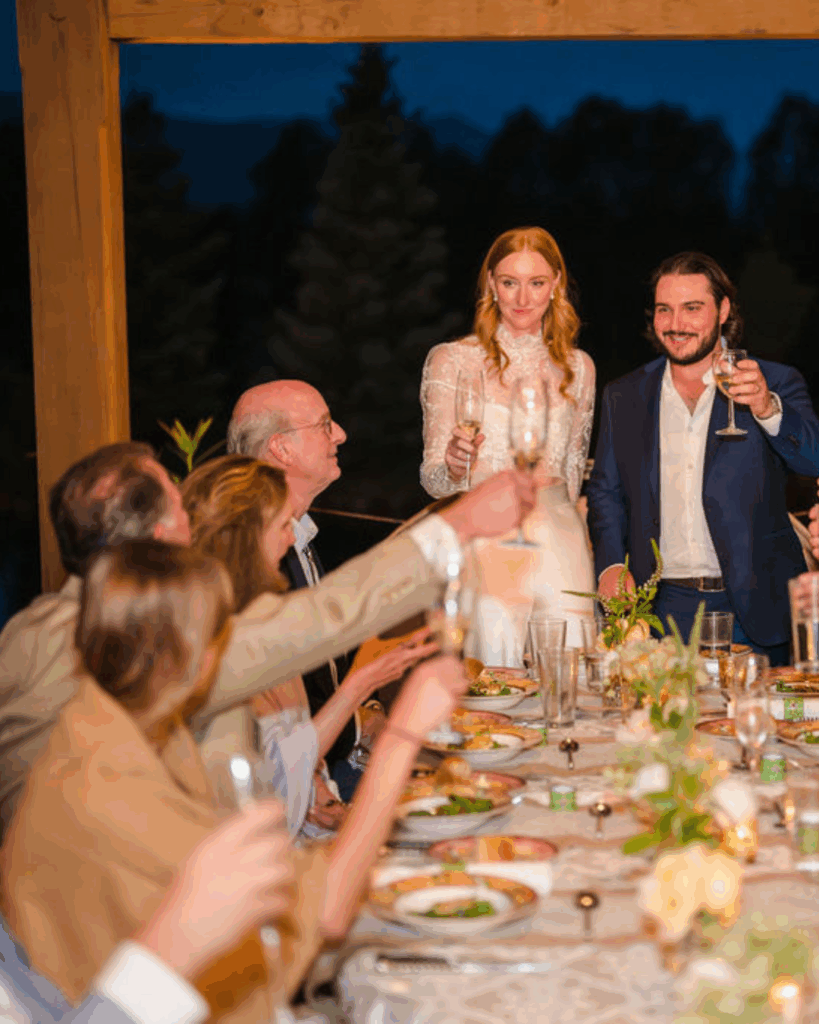 Guests raising glasses toward the newlyweds at dinner