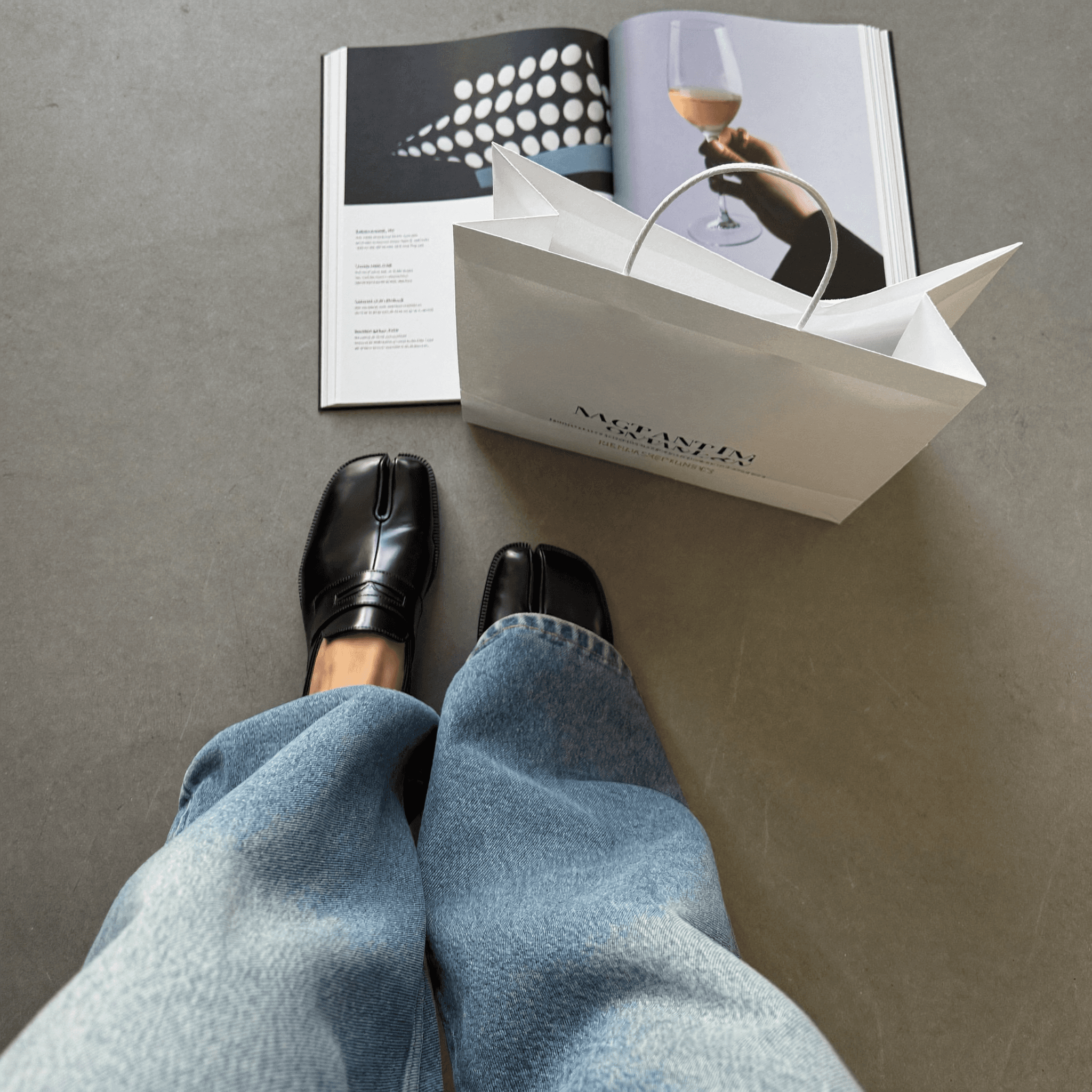 A woman in a teal dress sits in a dimly lit room, focused on her smartphone. A laptop and notepad are on the glass table, suggesting a working environment.