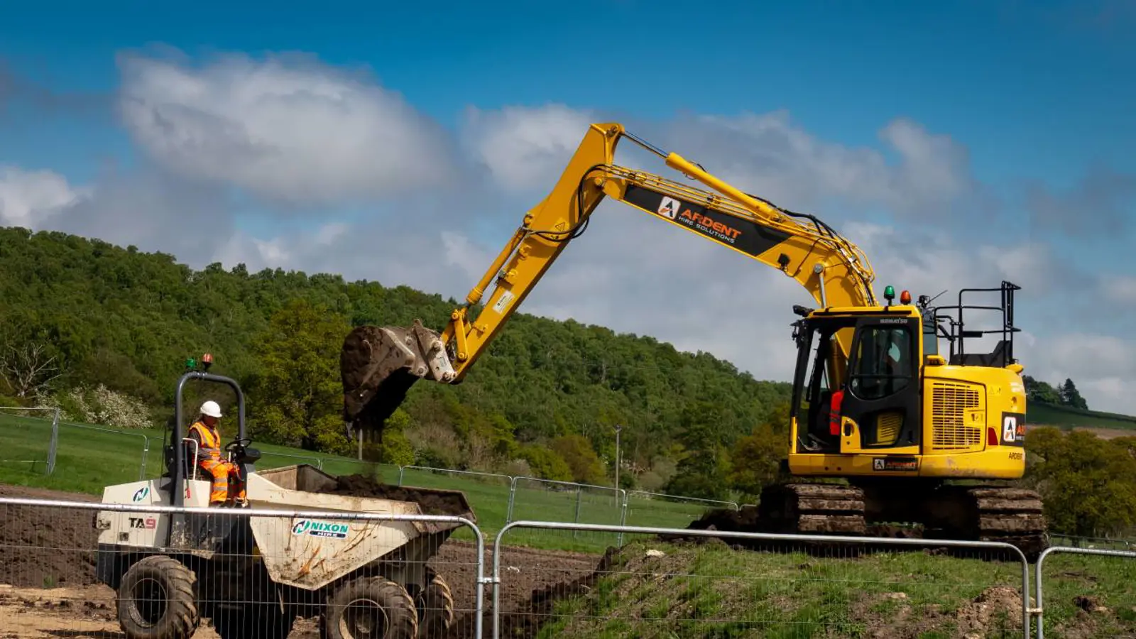 Excavator setting HDPE culvert pipe during drainage crossing installation in Kansas City.
