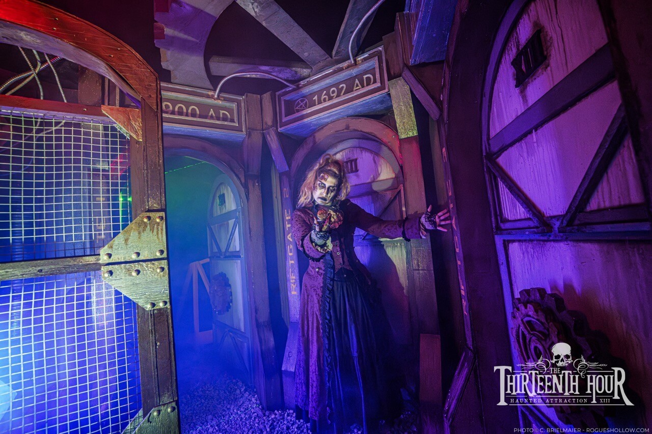 Costumed scare actor in a purple-lit industrial corridor