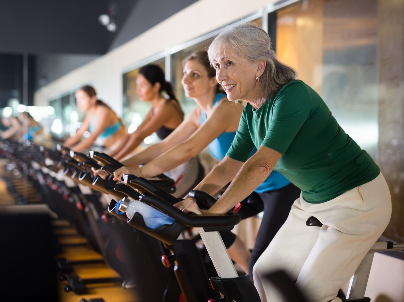older woman doing a class for biking for weight loss at the gym for joint-friendly exercise