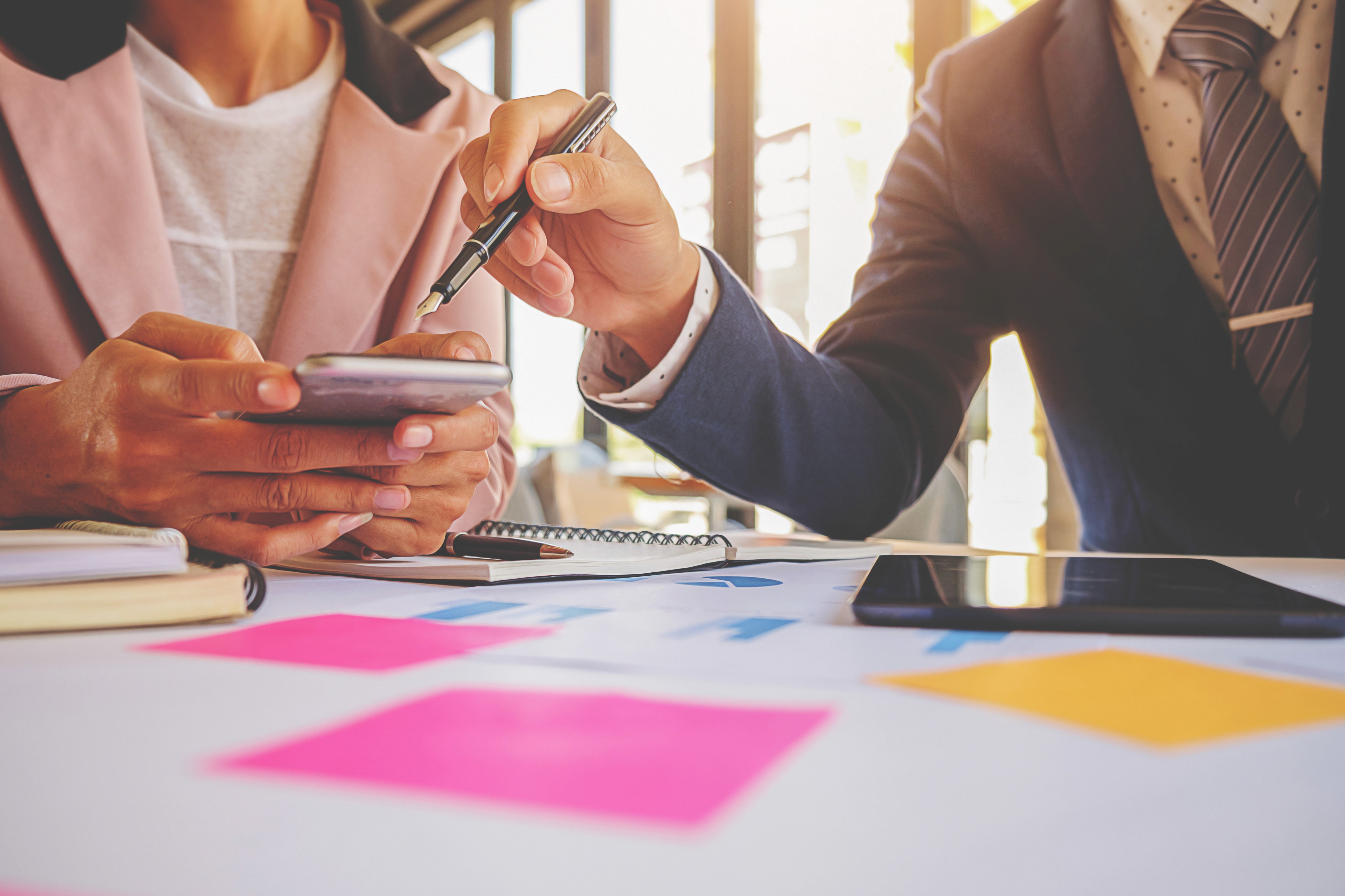 Two men discuss a project while standing at a laptop in an office.