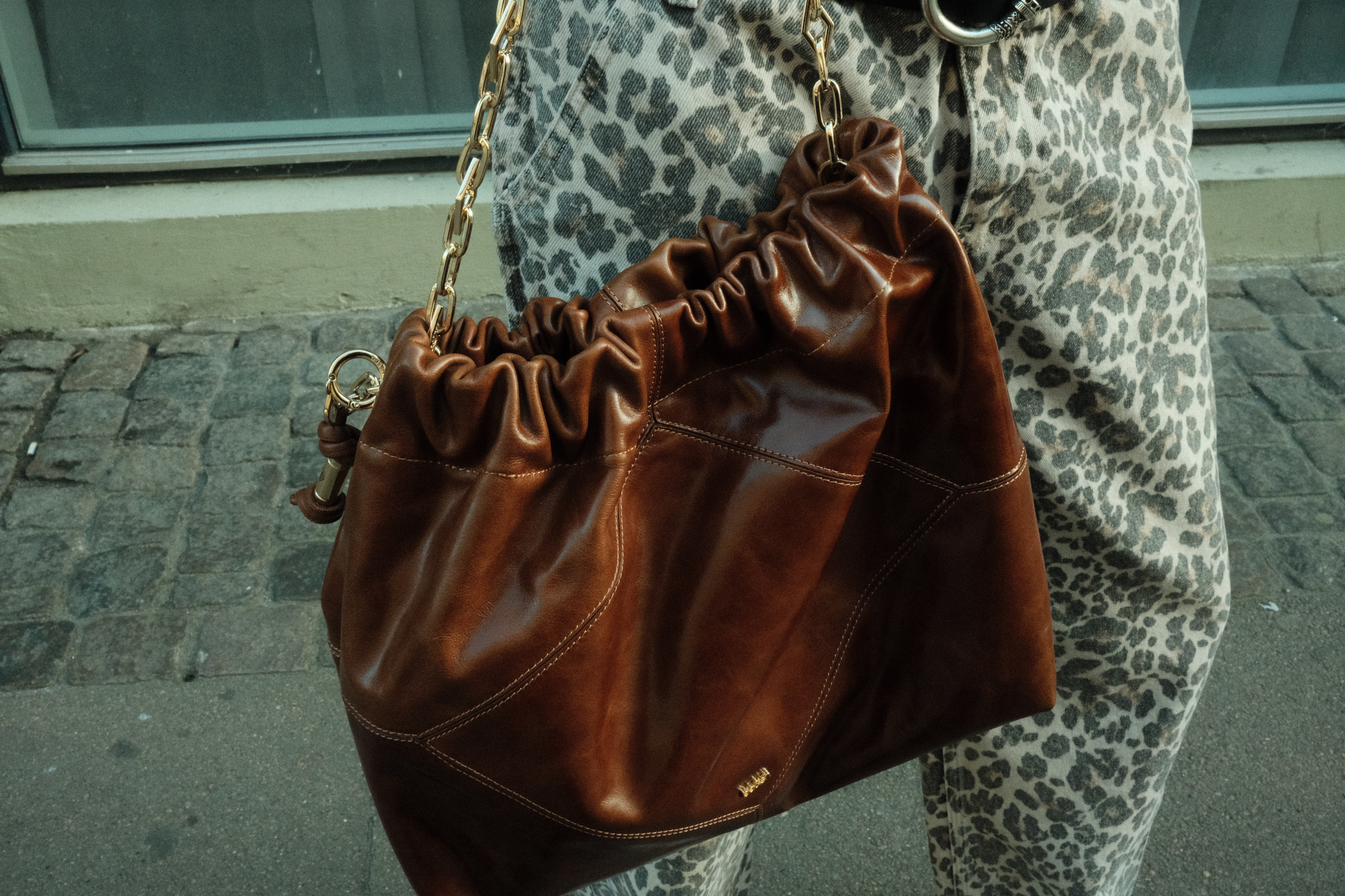 Backside of a person with a had and curly hairs sits in front of a screen in a room