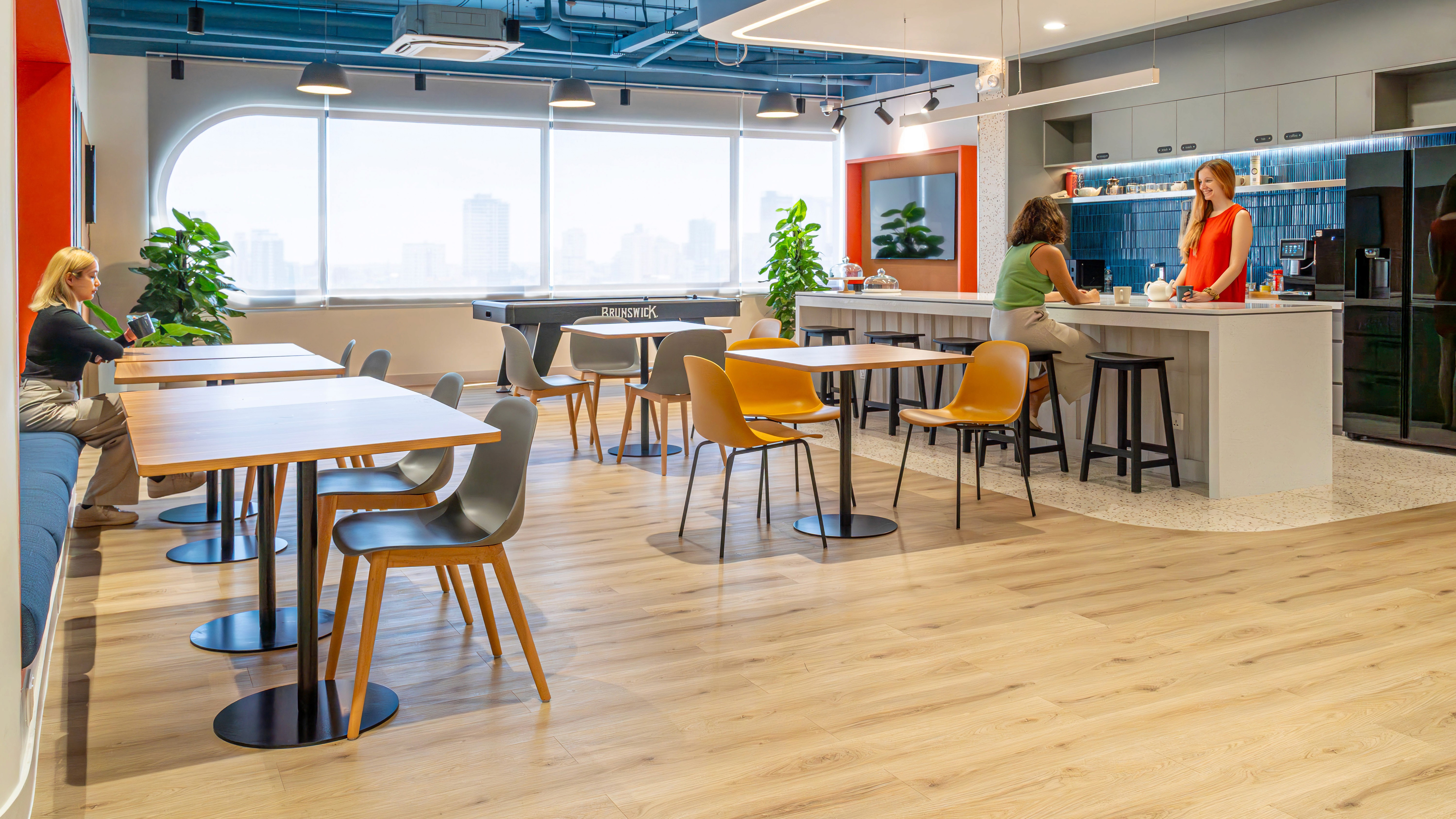 Pantry and breakout area with communal tables, bar counter, and integrated appliances supporting employee interaction and daily operations
