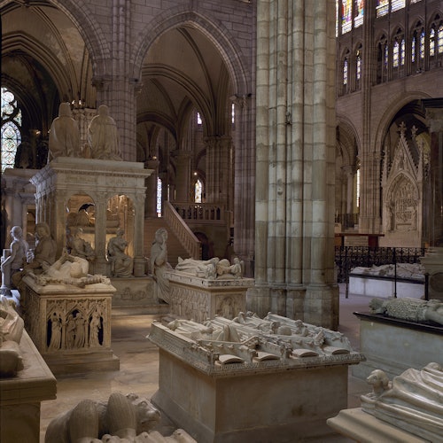 一座大教堂的内部，有众多石墓、雕像和华丽的建筑元素，置于拱形天花板之下。