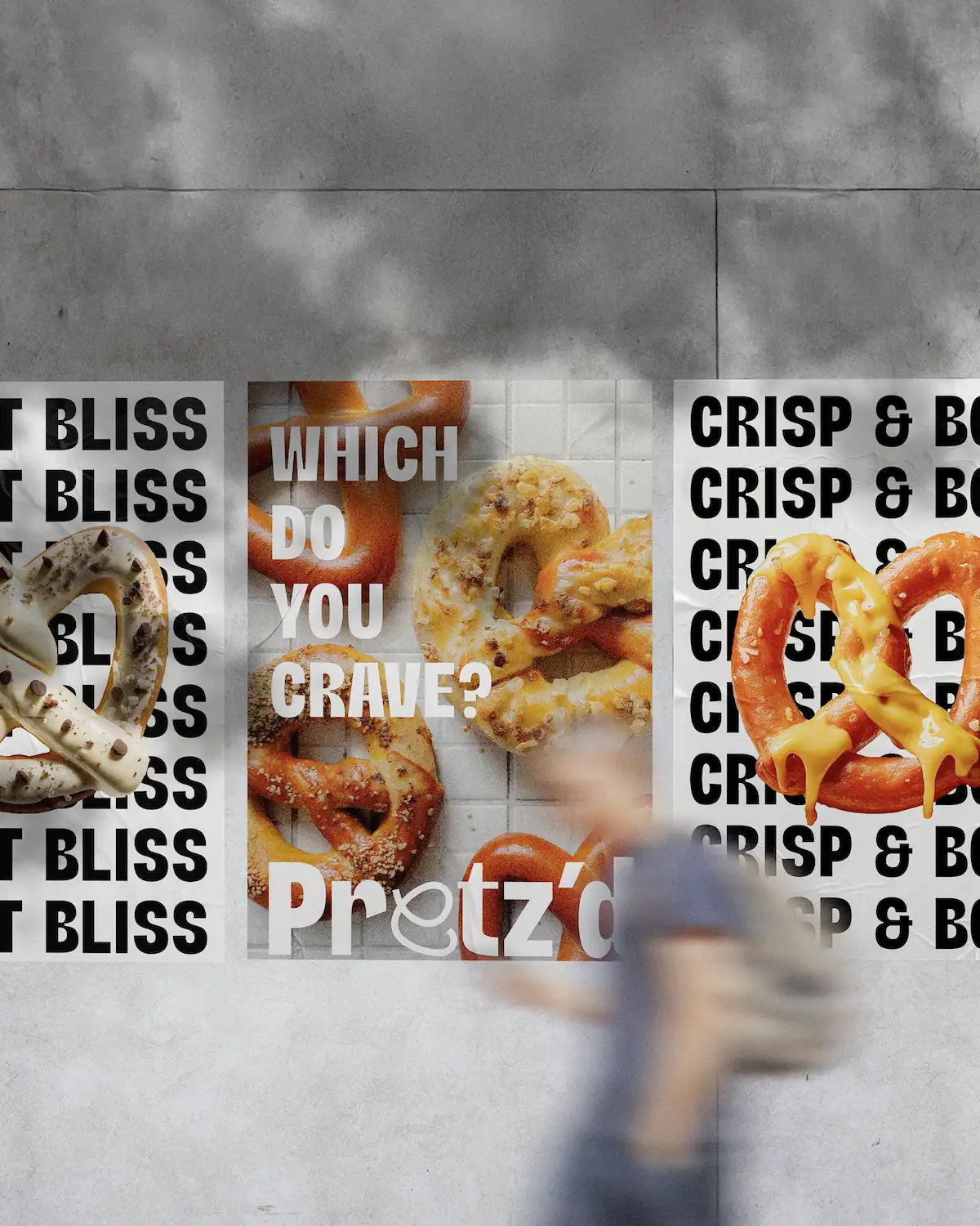 Triptyque d'affiches Pretz'd collées sur un mur urbain en béton, combinant visuels produits gourmands et typographie bold répétitive, passant flou au premier plan.