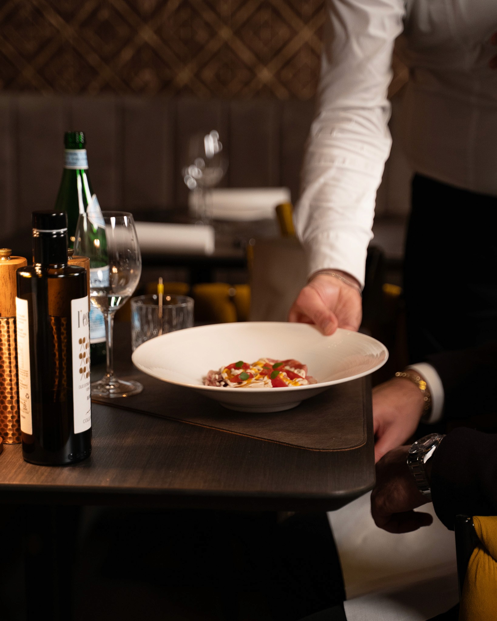 „Fein angerichteter Teller mit frischem Fisch-Carpaccio, buntem Blattsalat, Kräutern und essbaren Blüten, übergossen mit einem grünen Kräuteröl.“