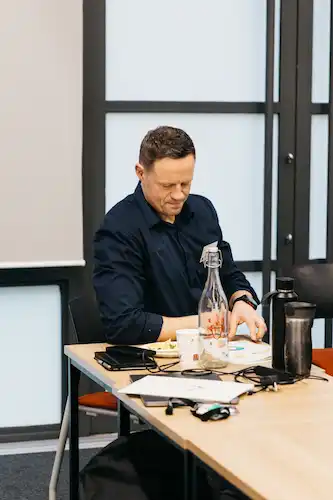 A person writing at a desk with papers and laptop.