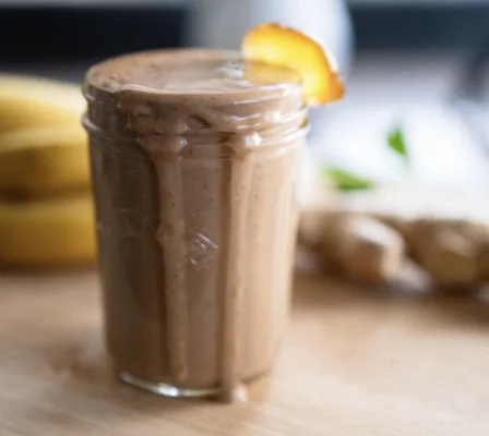 Overflowing mason jar with smoothie inside of it. Garnished with ginger