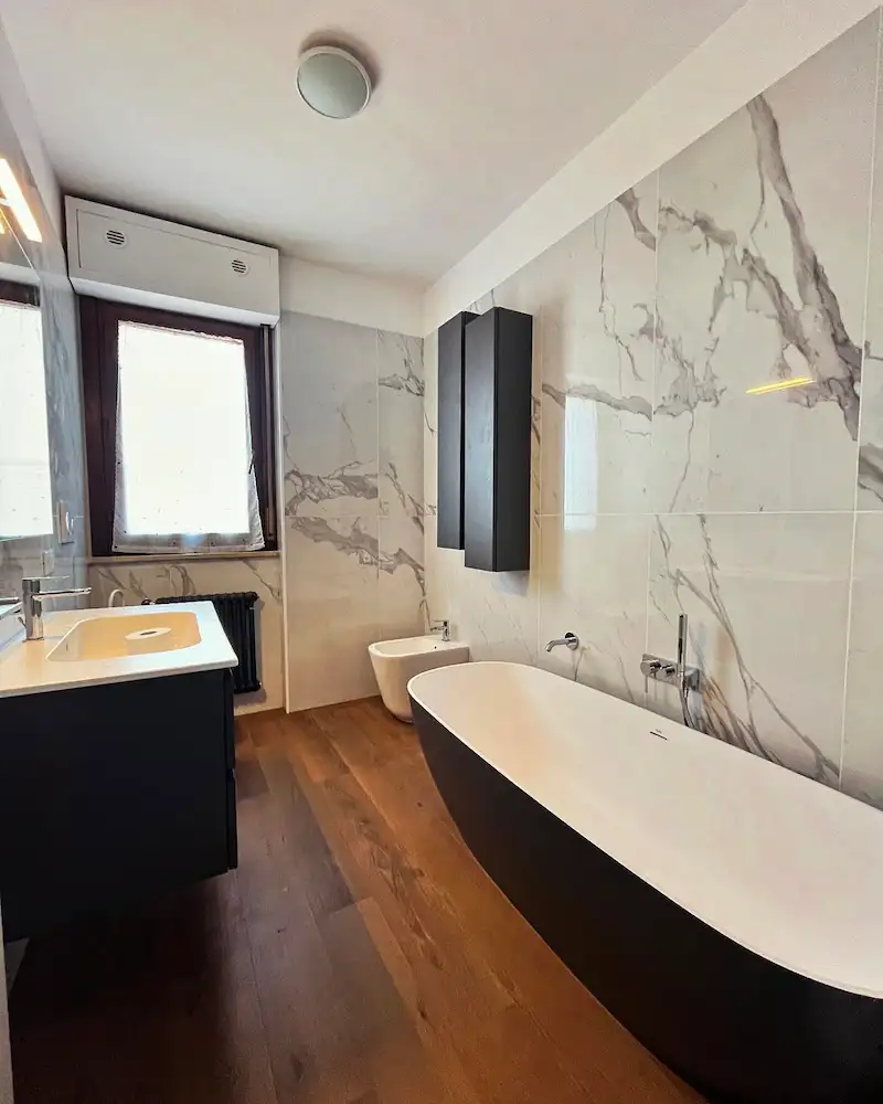 vasca da bagno di lusso con pareti rifinite in marmo e pavimenti in parquet