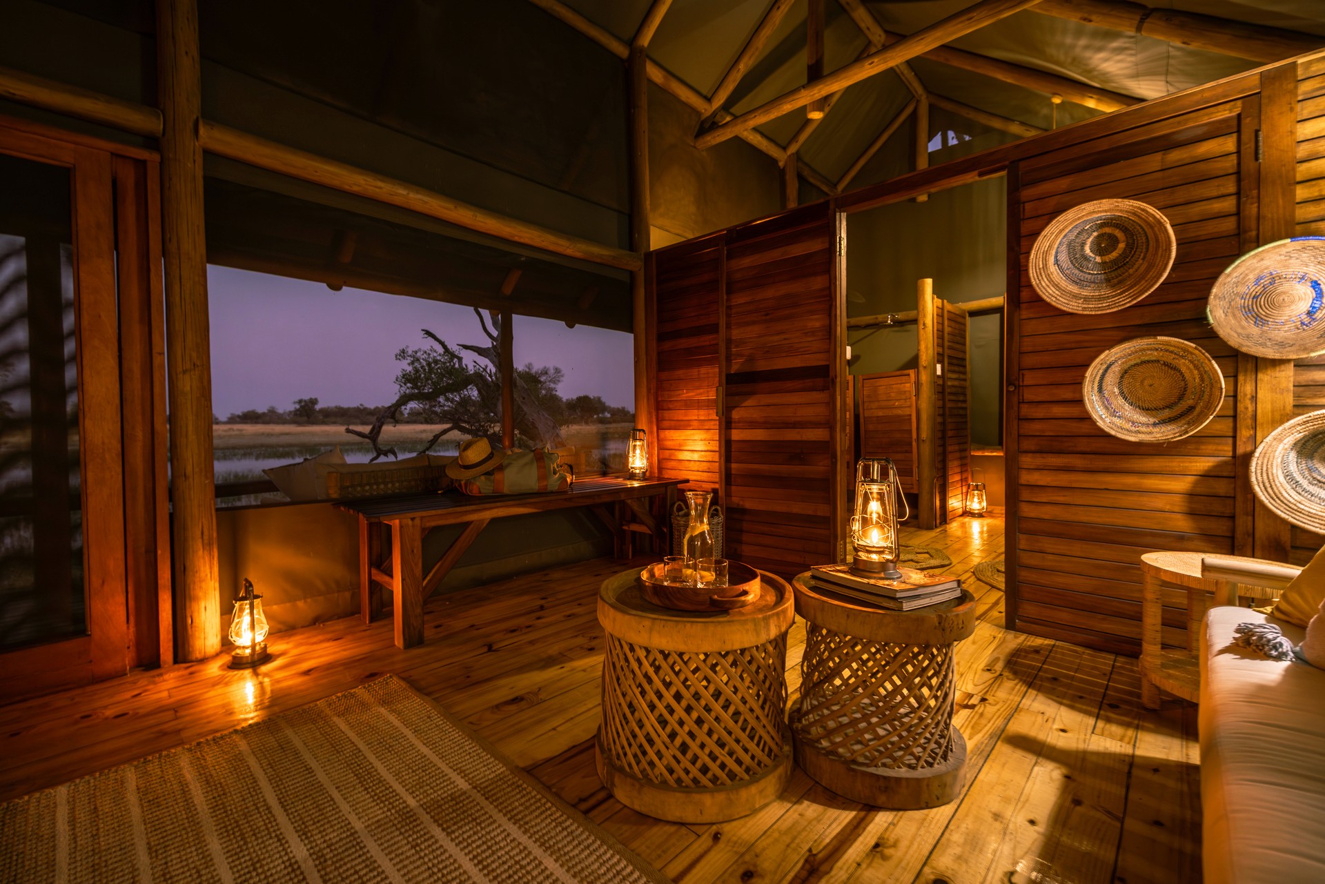 Lyxigt boende på Kujwana Delta Ride, Okavango Delta, Botswana. vacker inredning i olika trädslag och rotting, lounge-del av boende med usikt över natthimlen och Okavango Deltats floder