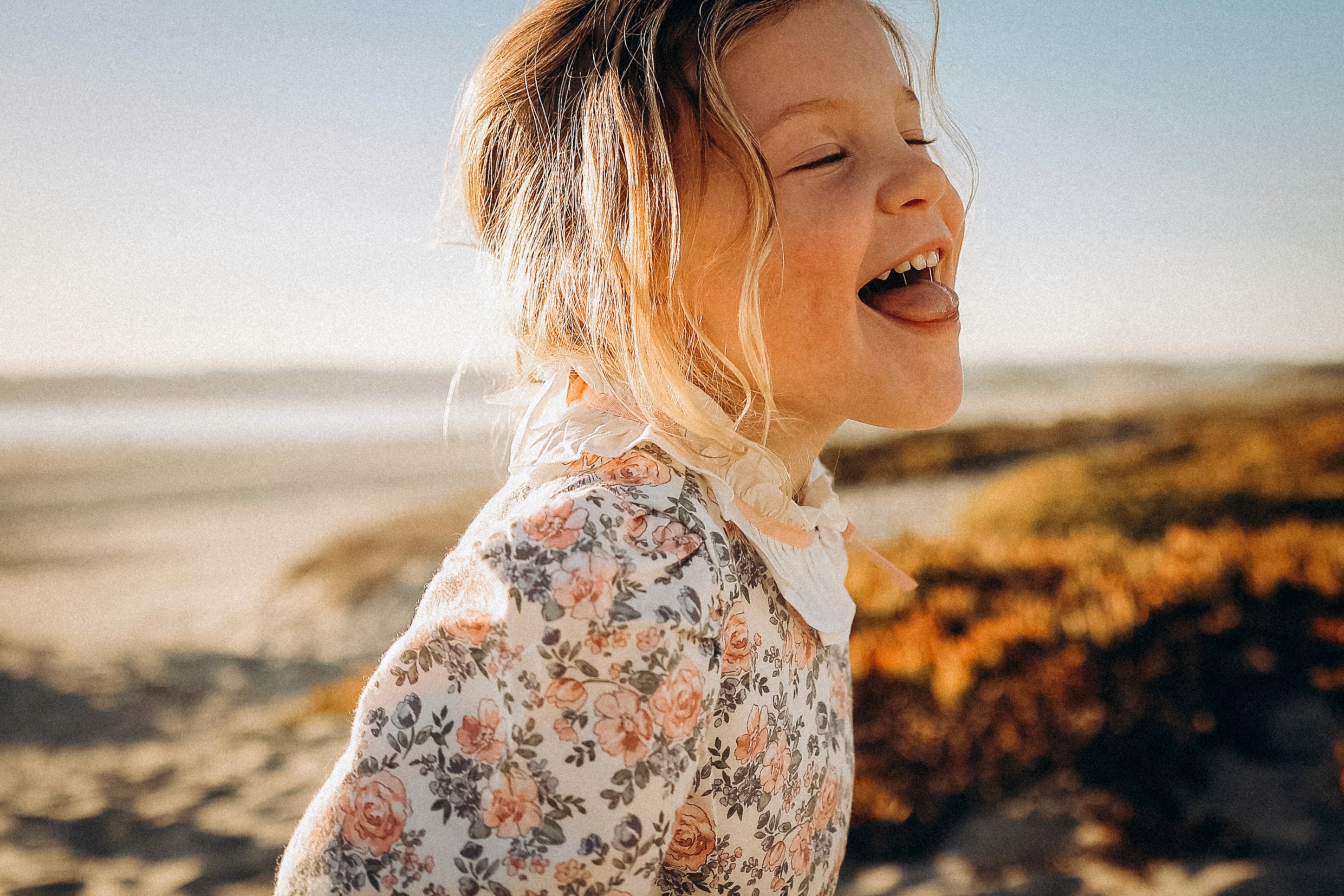 Smiling girl in warm sunset tones during a playful lifestyle family moment.