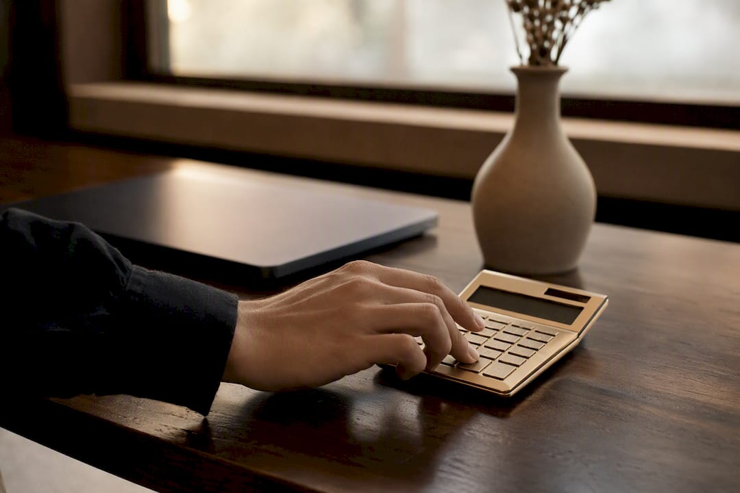 Hand holding golden calculator on dark desk