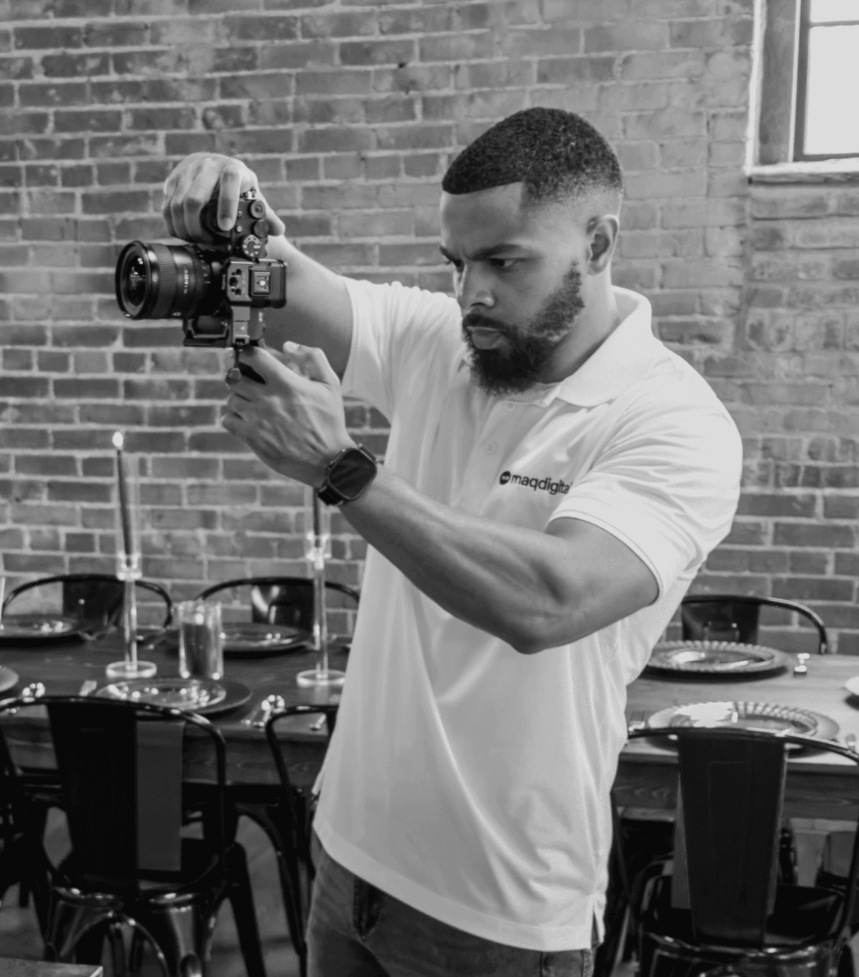 Close-up portrait of a person wearing a gray insulated hooded jacket with the hood up, showing their face framed by the hood against a light background.