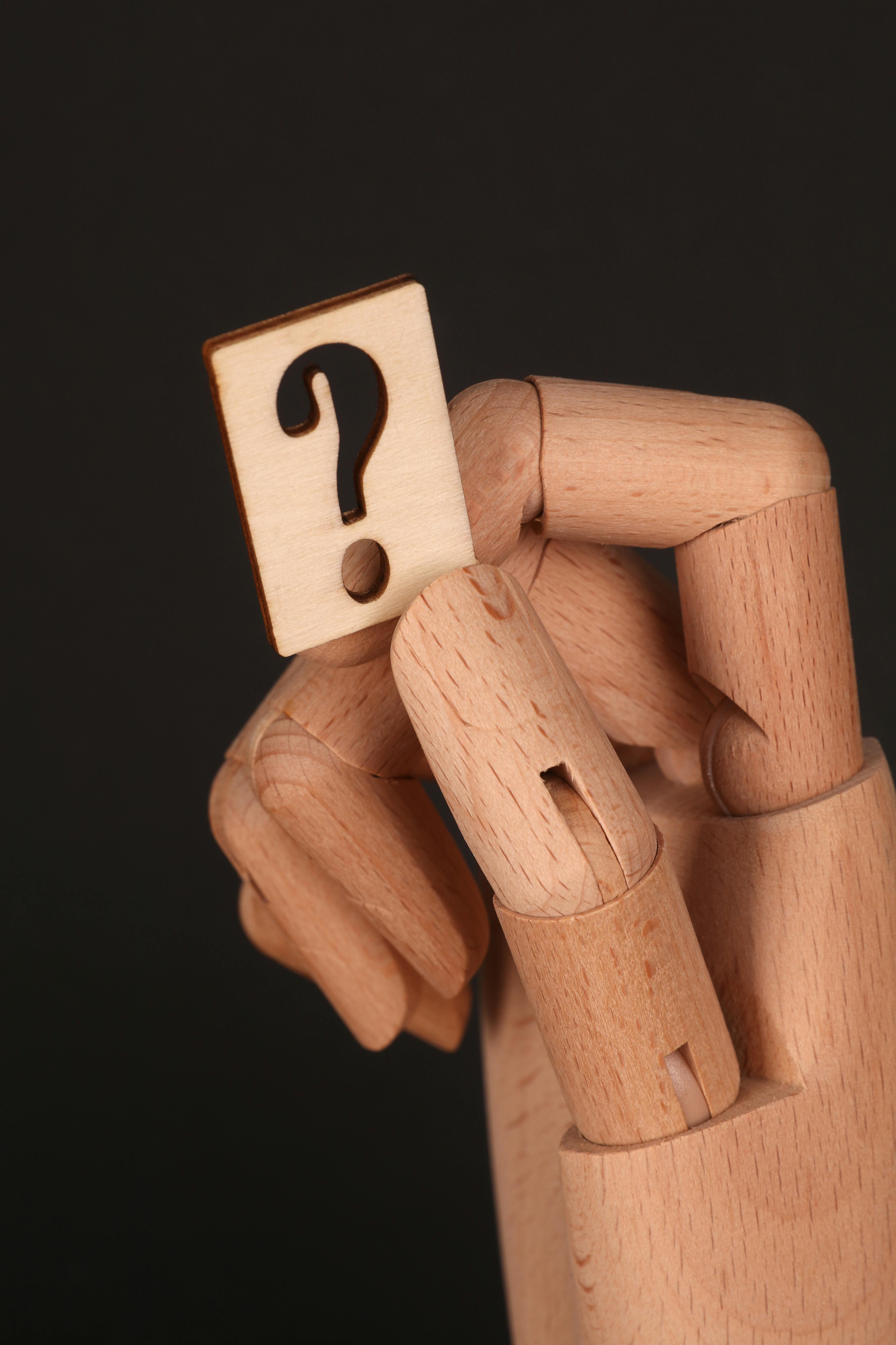 A hand holding a question mark sign