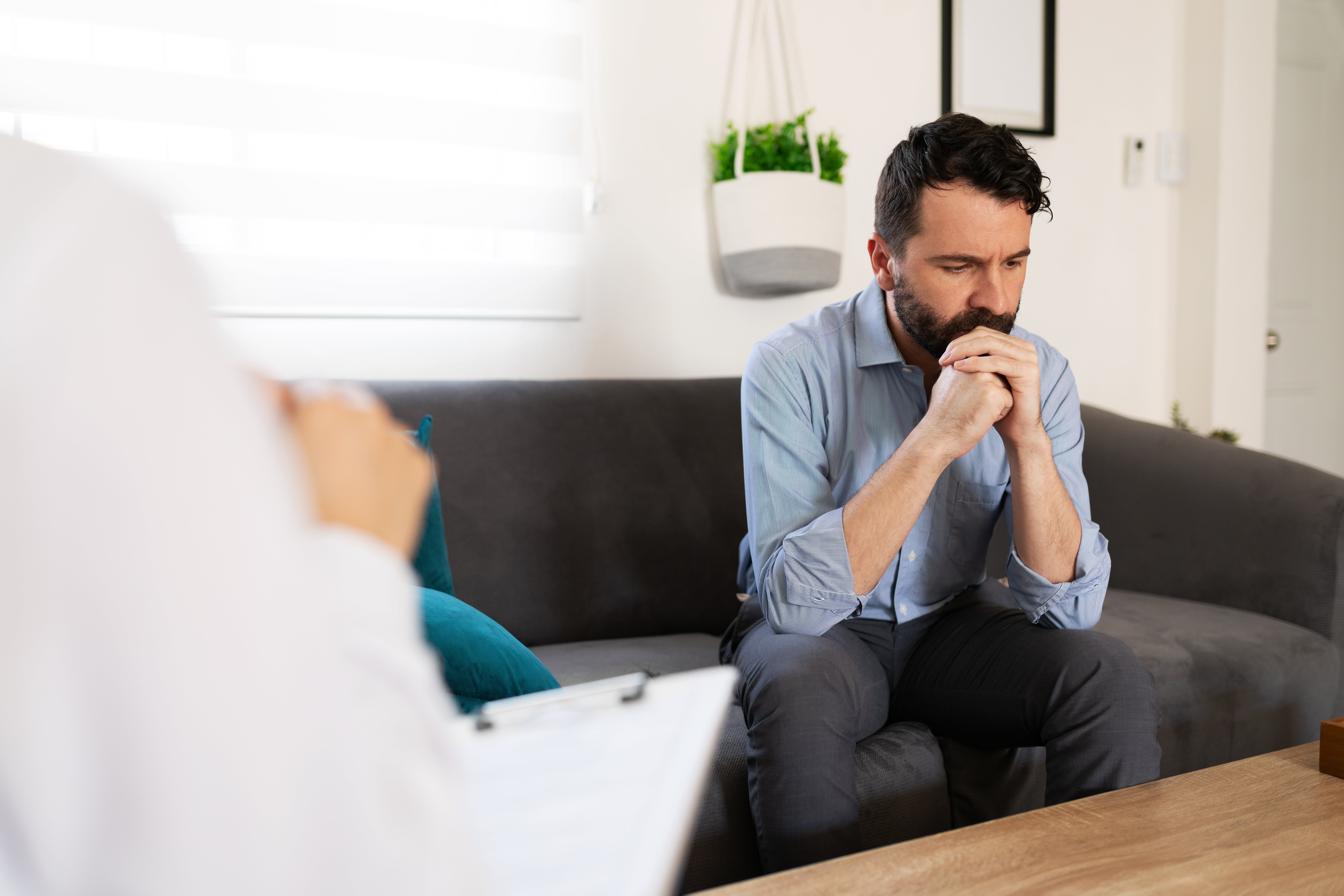 A man in counselling, his hands resting on his chin