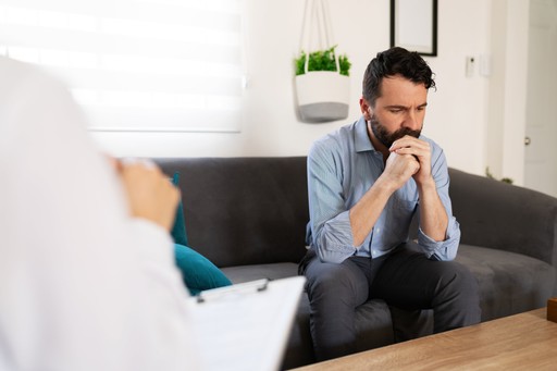 A man in counselling, his hands resting on his chin