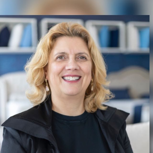 A young person with long, wavy hair sits in front of a plain background, looking directly at the camera.