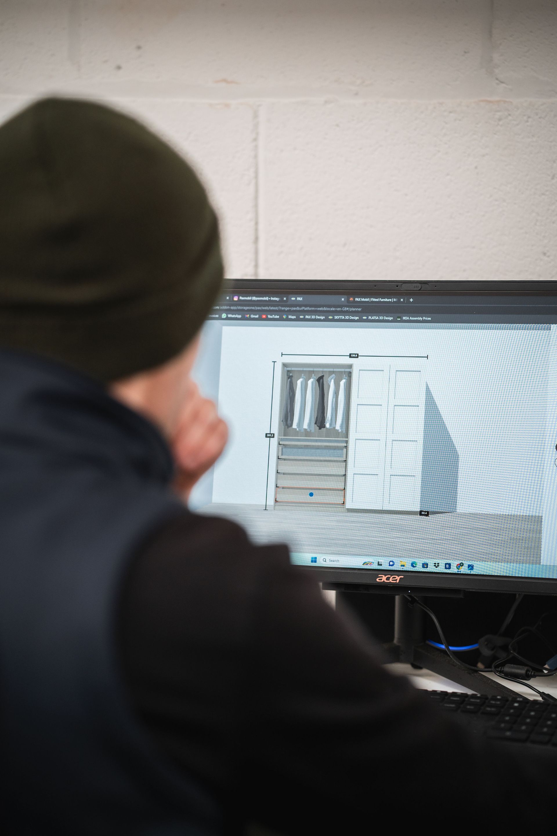 over-the-shoulder angle of a man looking at a computer screen with a 3d rendered wardrobe