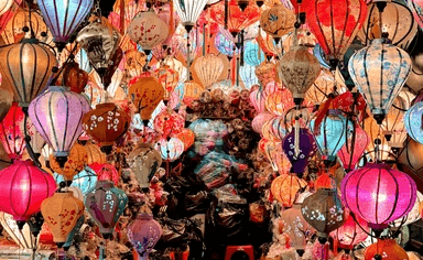 A rustic outdoor dining table set with wine glasses, cutlery, bread, and olives sits amidst lush vineyard rows, with a historic Tuscan villa in the background under a serene sky, capturing the essence of a picturesque Italian countryside landscape.