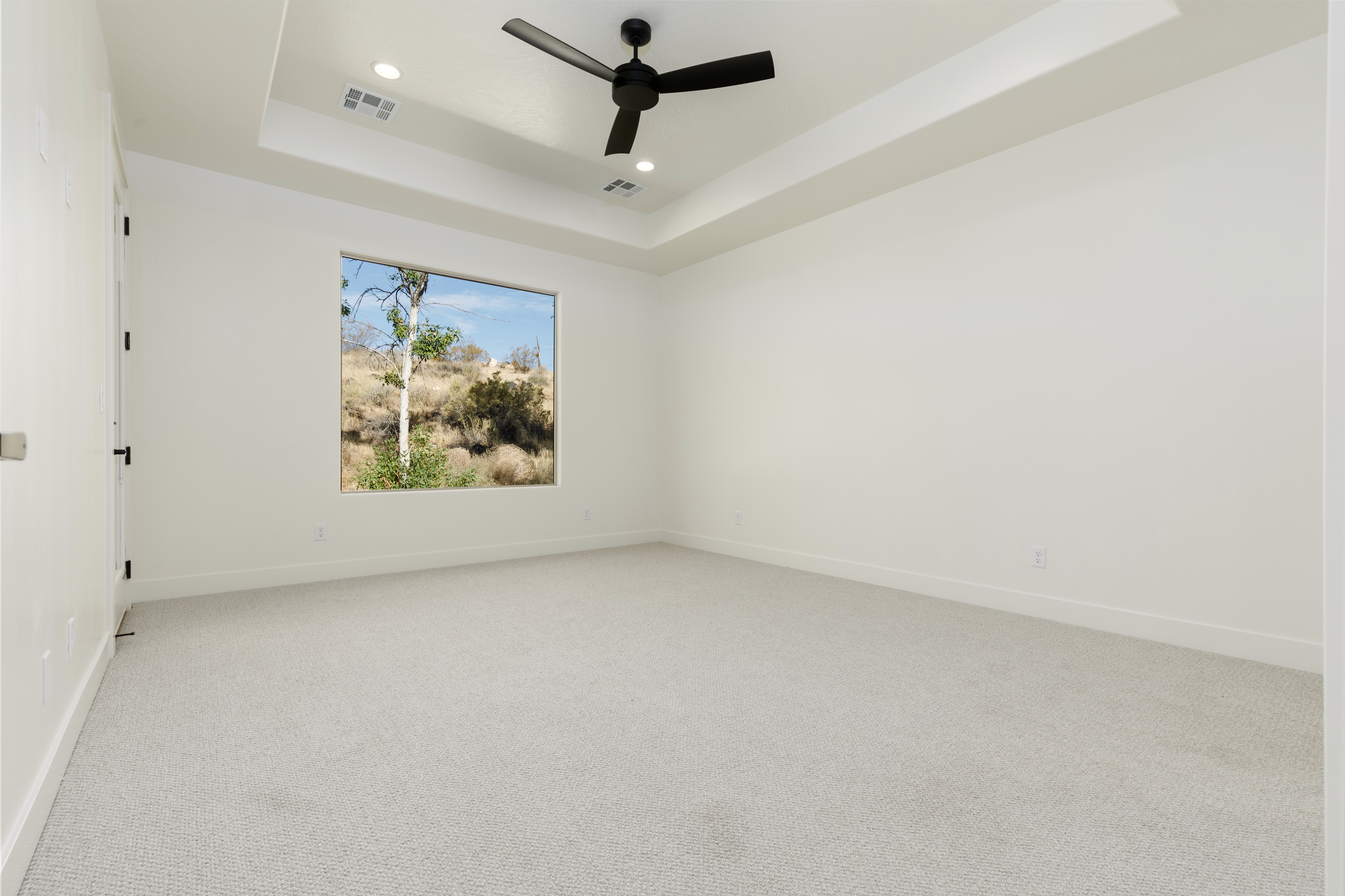 Primary bedroom at Mountain View’s Cove featuring a tray ceiling and soft natural lighting in Hurricane, Utah.