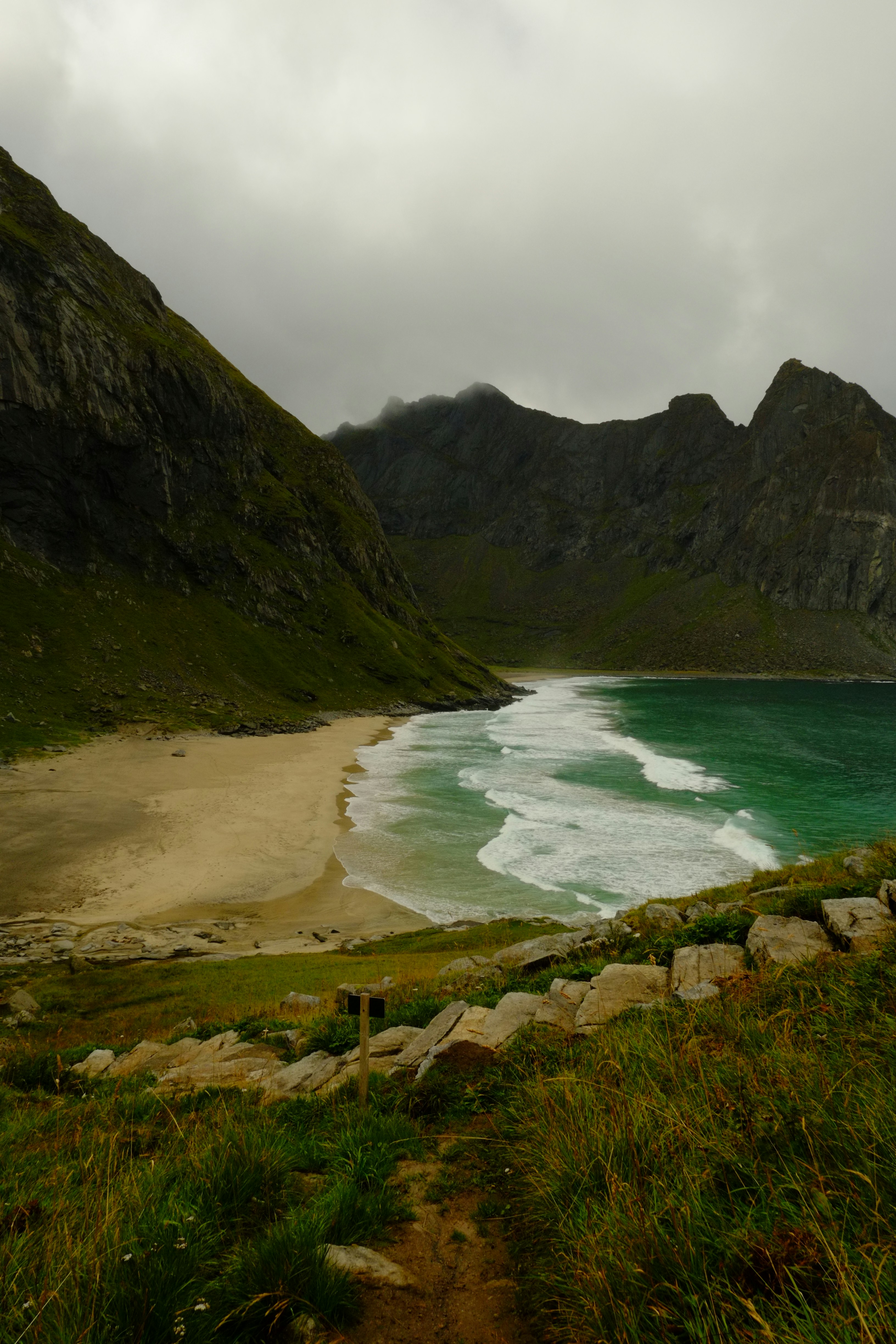 Sandy beach with waves between green mountains