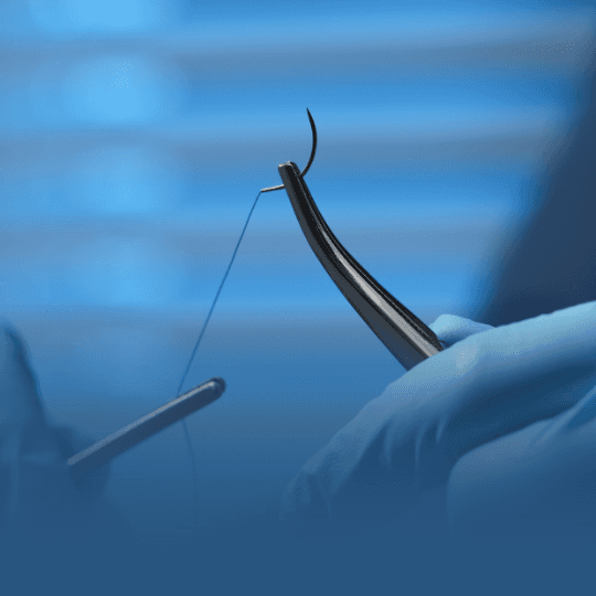 Mãos com luvas manipulando sutura cirúrgica