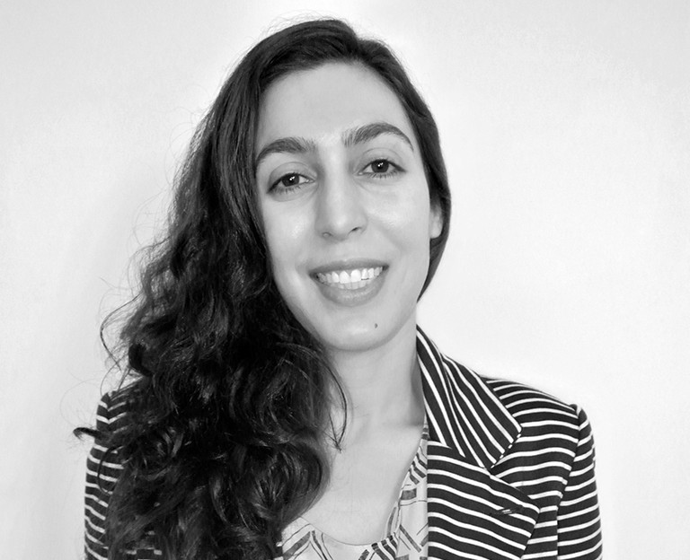 A black and white photo of a woman smiling while wearing a striped shirt.