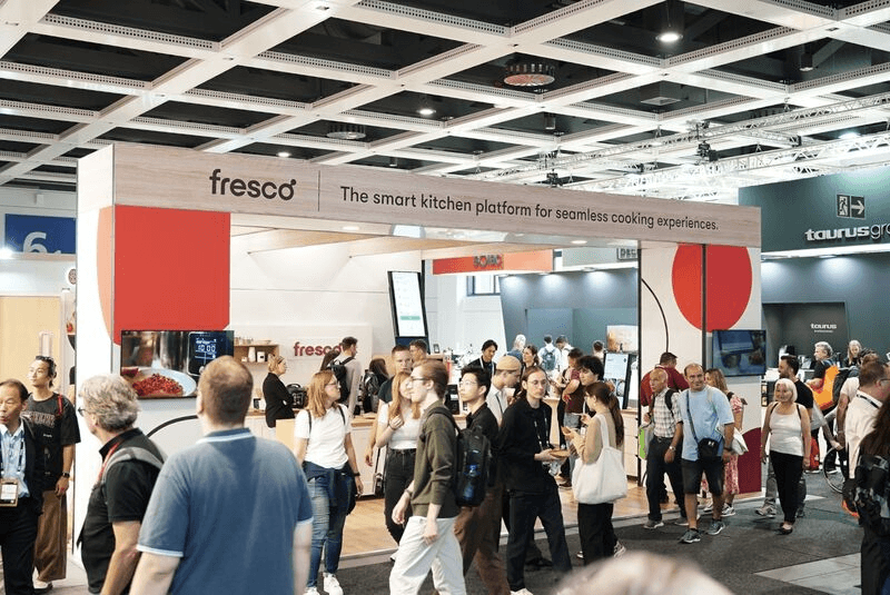 Crowd gathers at a Fresco booth with signage reading "The smart kitchen platform for seamless cooking experiences" at a busy trade show